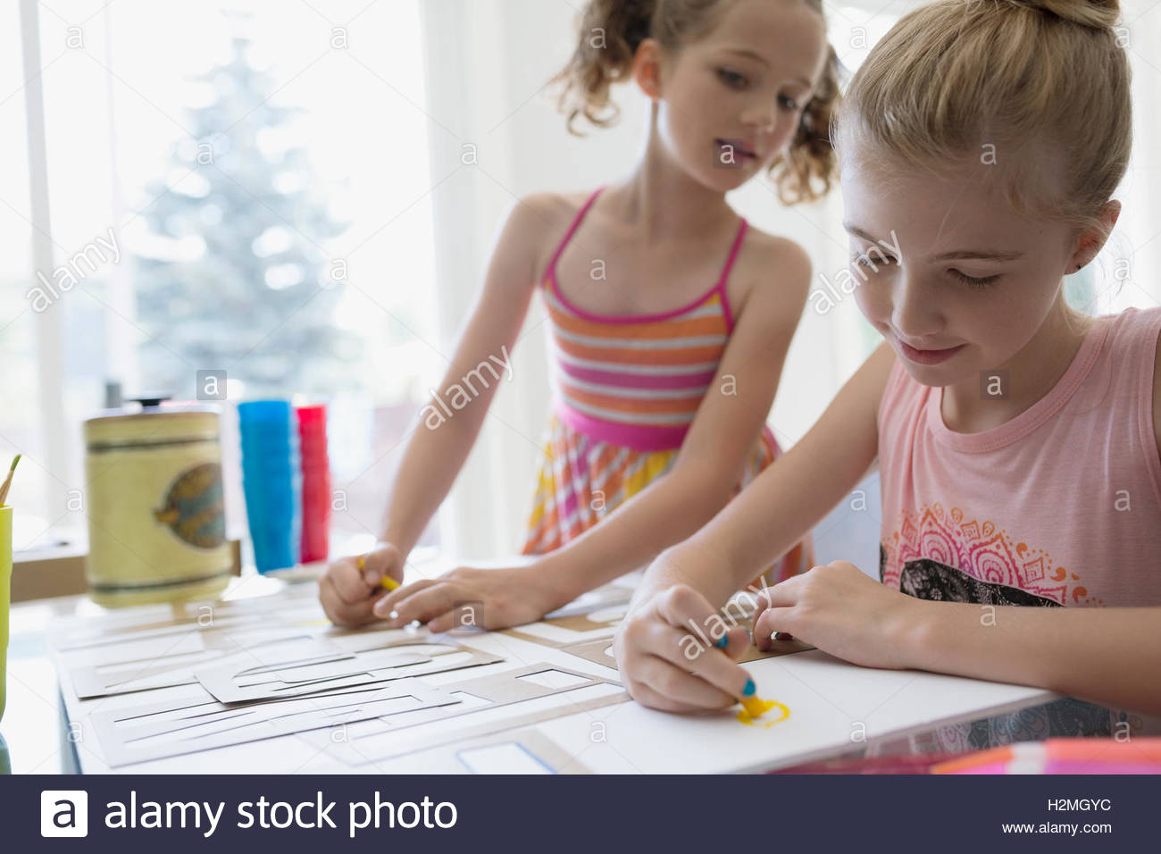 Girls coloring and using stencils at dining table Stock Photo