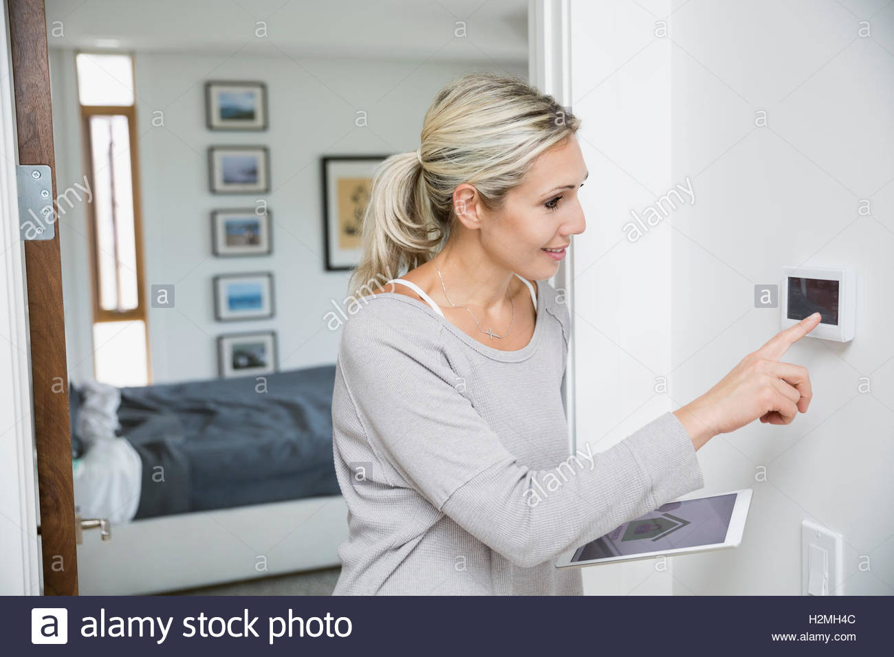Woman programming alarm and home security app on digital tablet Stock Photo