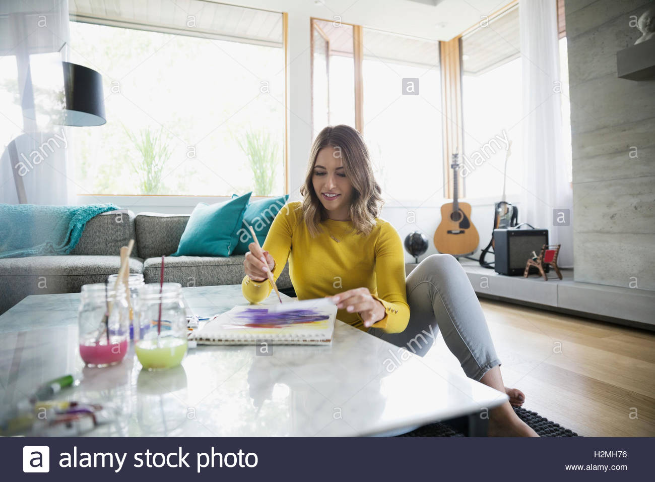 Young woman painting with watercolors in living room Stock Photo - Alamy