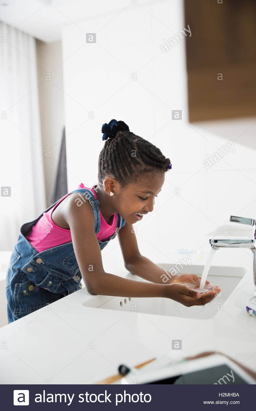 Girl washing face at sink in bathroom Stock Photo Alamy