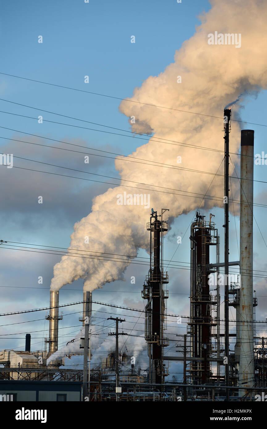 Smokestacks from oil refinery releasing thick smoke into the atmosphere Stock Photo