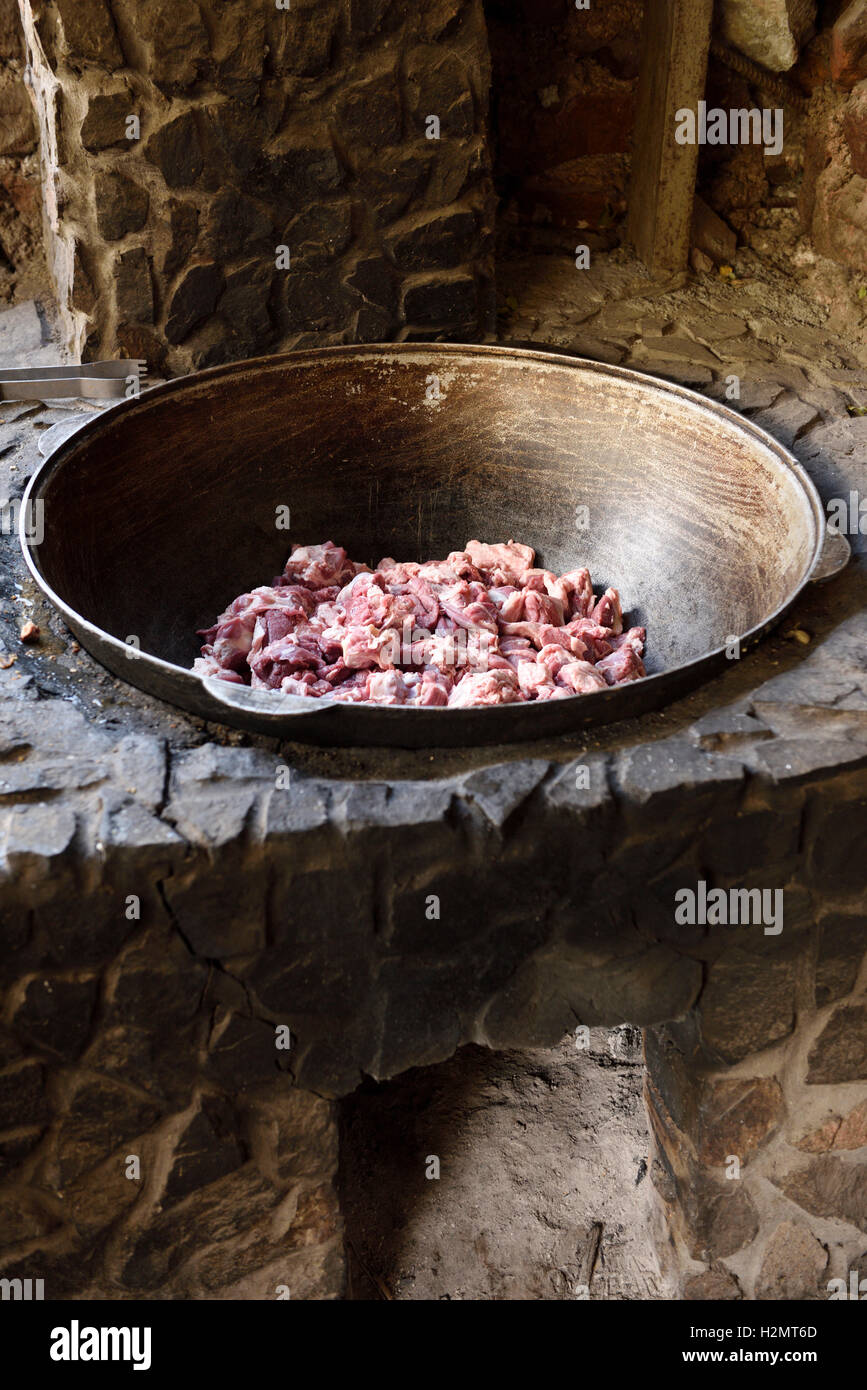 Outdoor stone cooking oven fit with steel bowl with raw lamb Kazakhstan Stock Photo