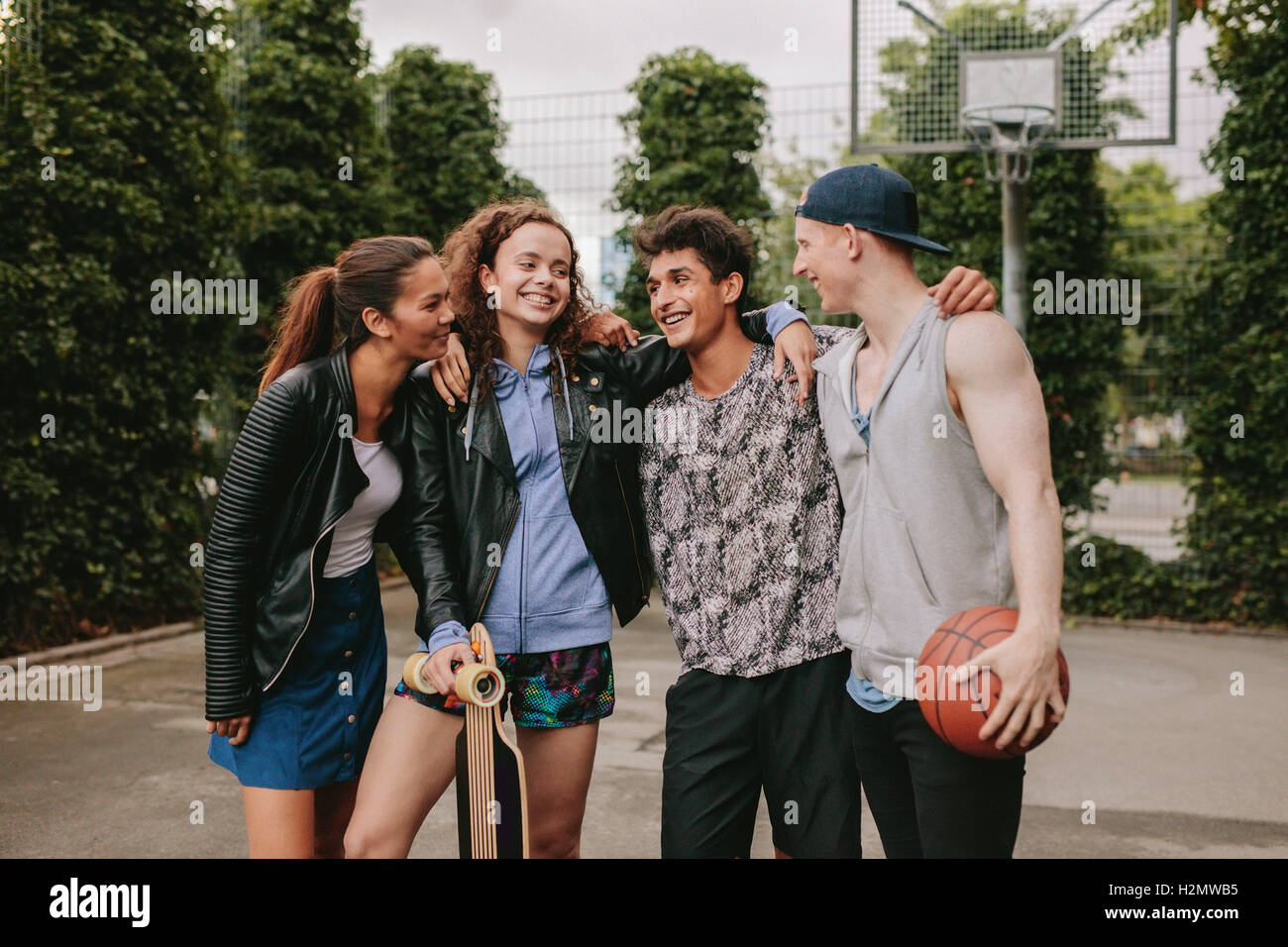 Portrait of four young friends standing together. Mixed race group of people having fun outdoors. Stock Photo