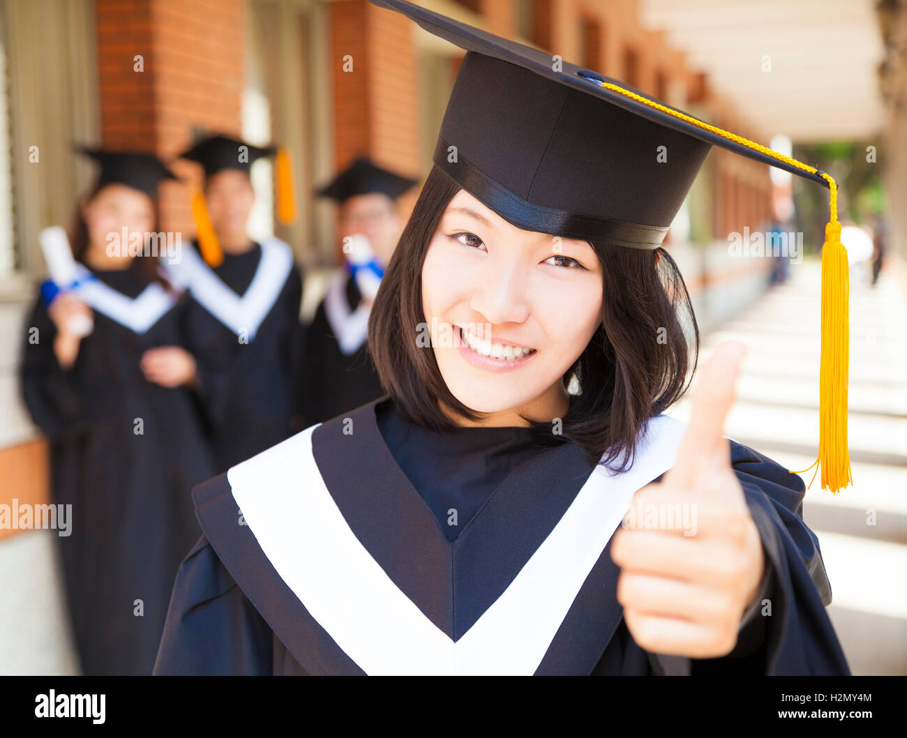 closeup pretty college graduate thumb up with classmates Stock Photo ...