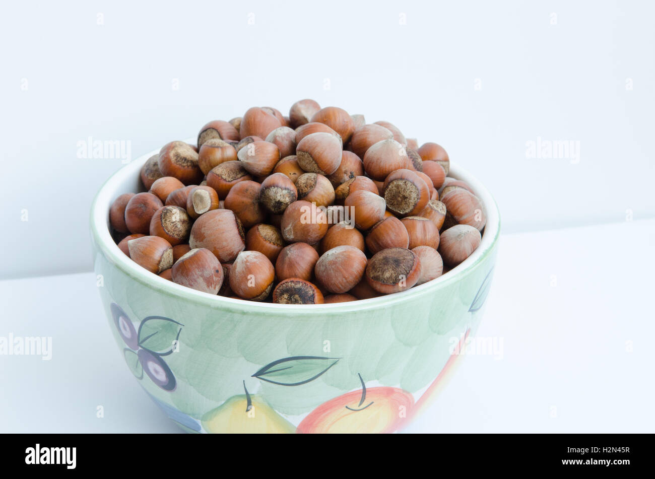 bowl of unshelled hazelnuts against a white background Stock Photo