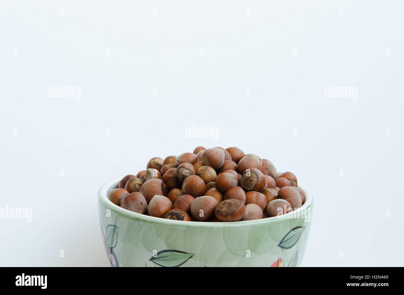 bowl of unshelled hazelnuts against white background Stock Photo