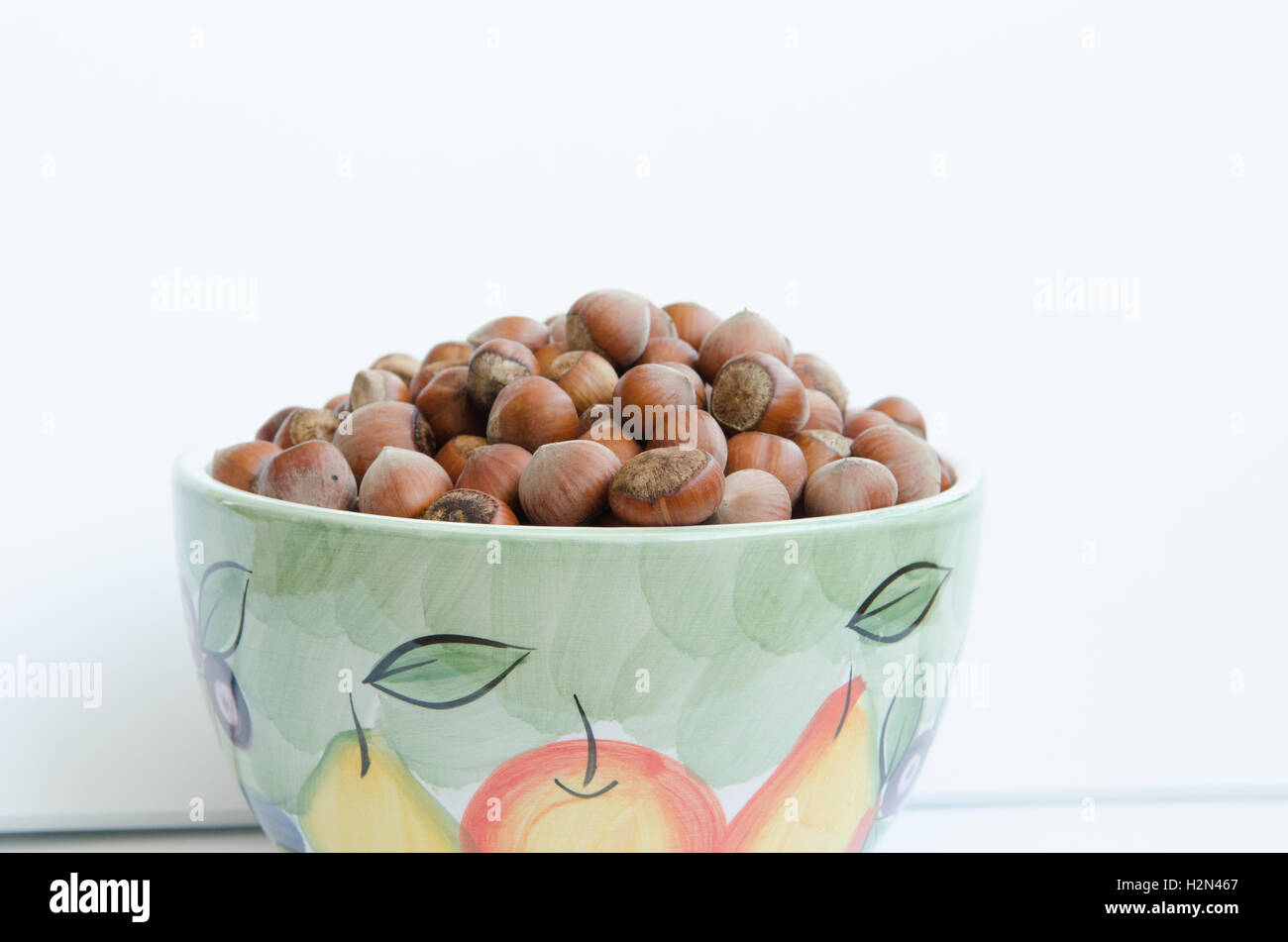 bowl of unshelled hazel nuts isolated against a white background Stock Photo