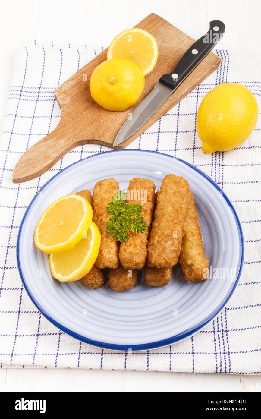 deep fried fish finger made from alaska pollock fish with slice lemon and parsley on a plate