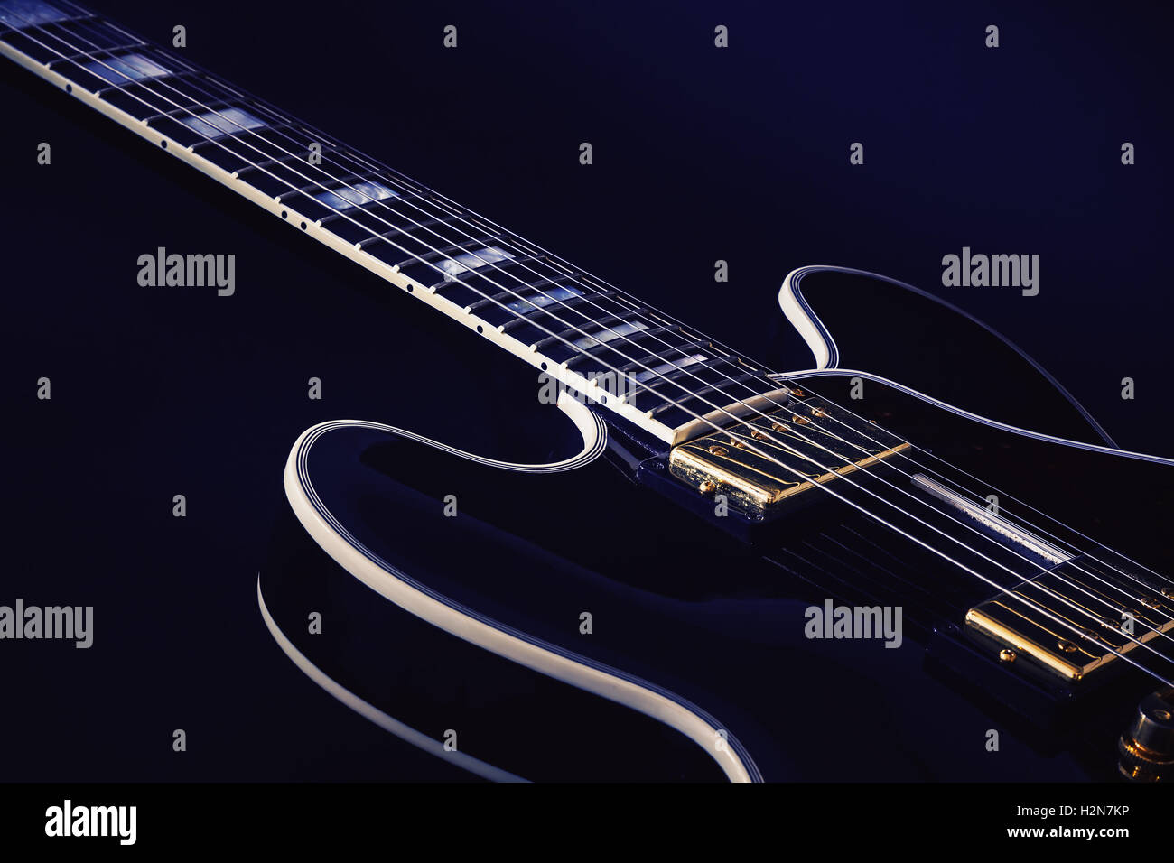 Neck and body part of an electric guitar, blue background. Stock Photo