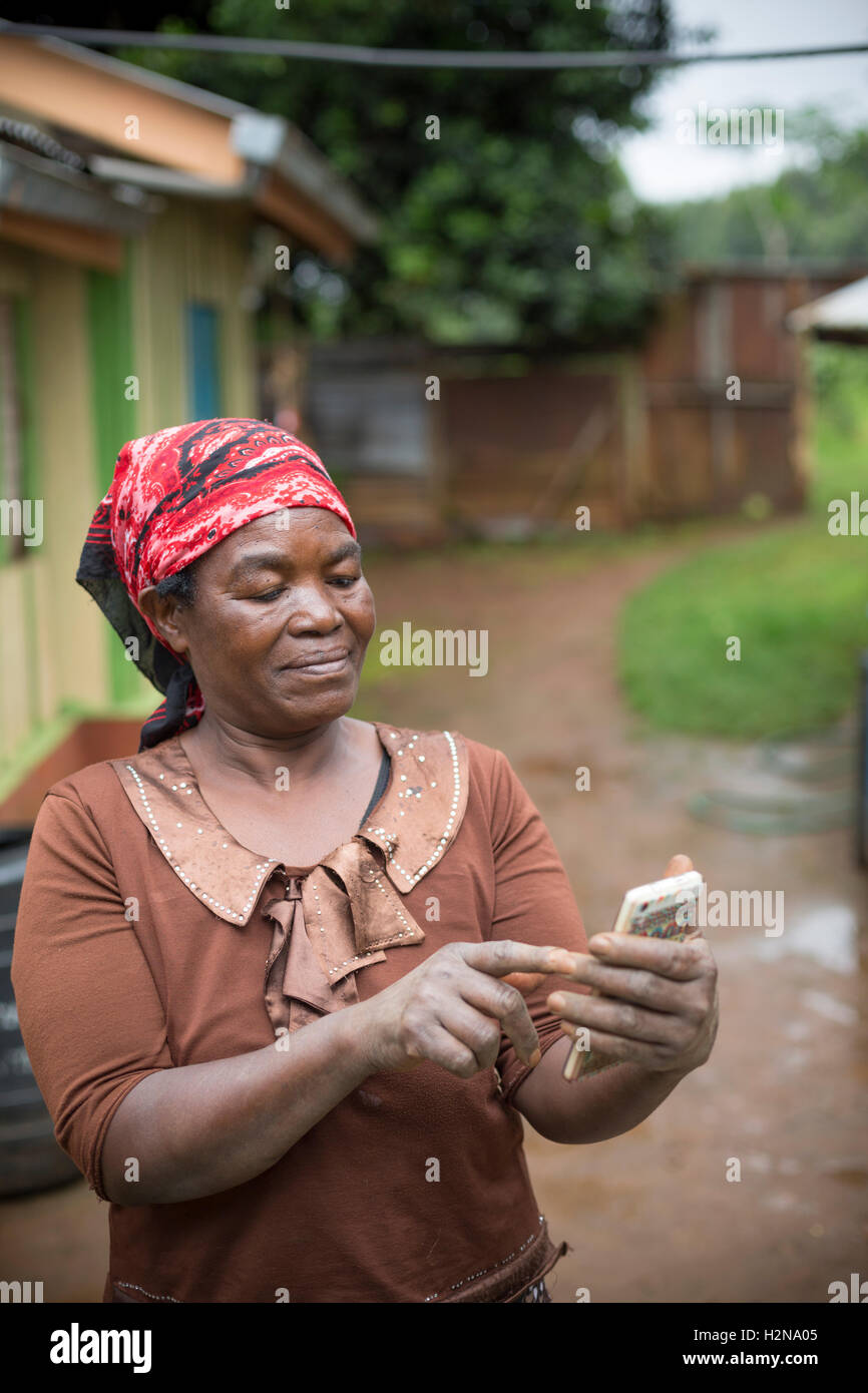 A woman sends a tex message in rural Kirinyaga County, Kenya. Stock Photo
