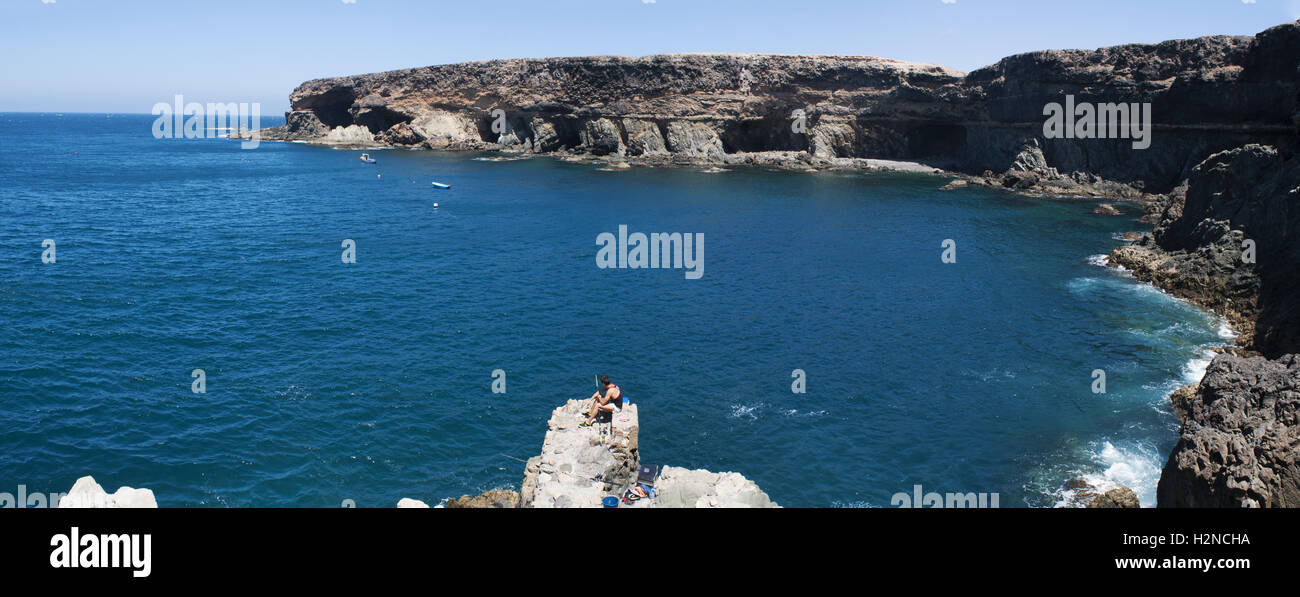 Fuerteventura, Canary Islands, North Africa, Spain: a fisherman seated on a rock in front of the famous caves of Ajuy, a little village of the west Stock Photo