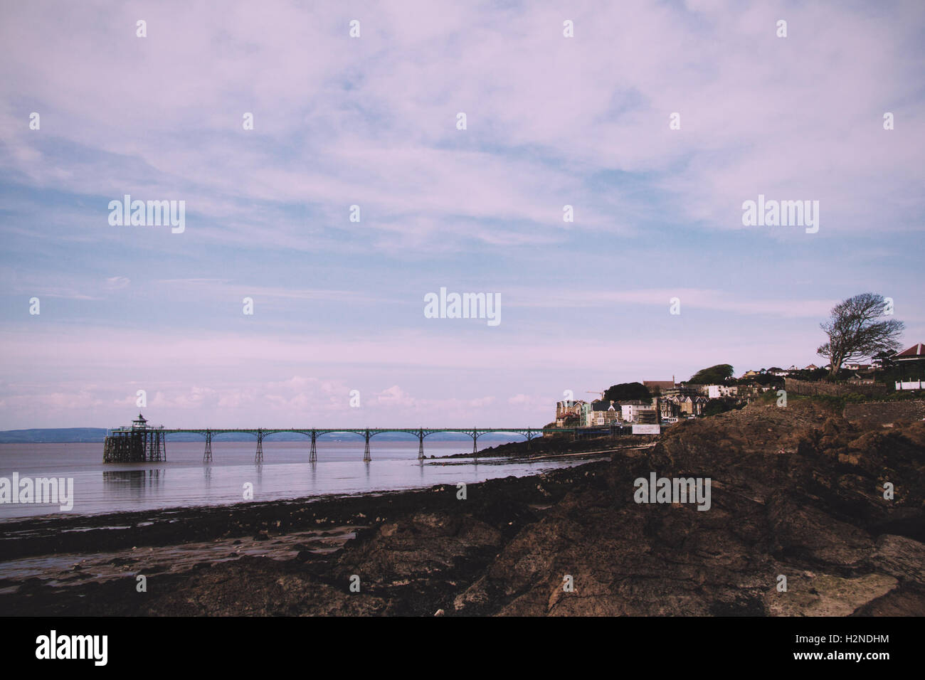 View over rocks at Clevedon sea front, including pier in background. Vintage Retro Filter. Stock Photo