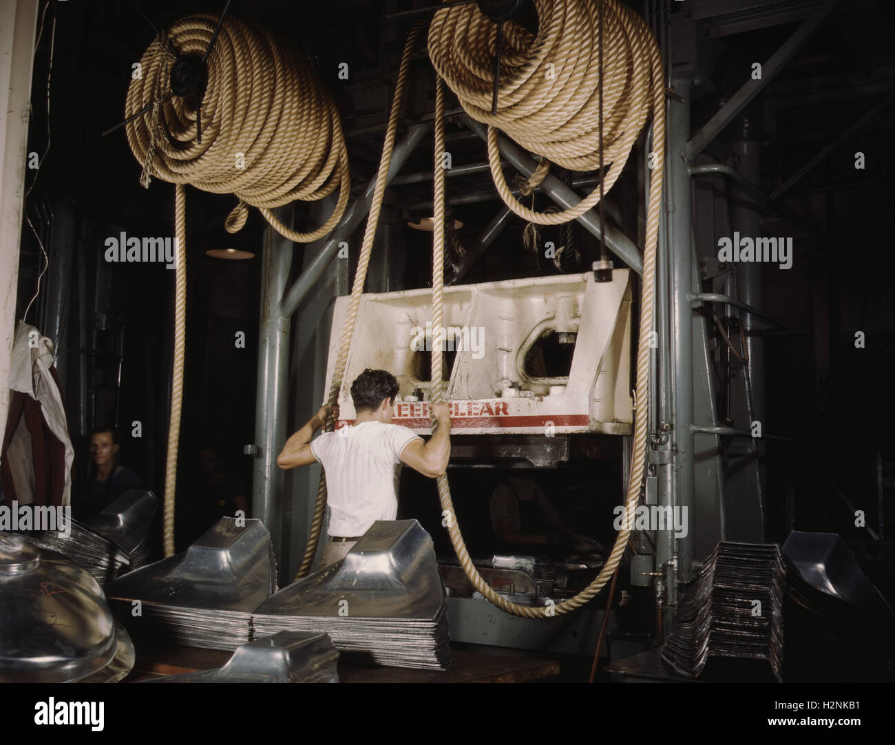 Factory Worker assisting Huge Drop Hammer with Hemp Rope to Manufacture Sheet Metal Parts for United Nations Bombers and Fighter Planes, North American Aviation, Inc, Inglewood, California, USA, Alfred T. Palmer, U.S. Office of War Information, October 1942 Stock Photo