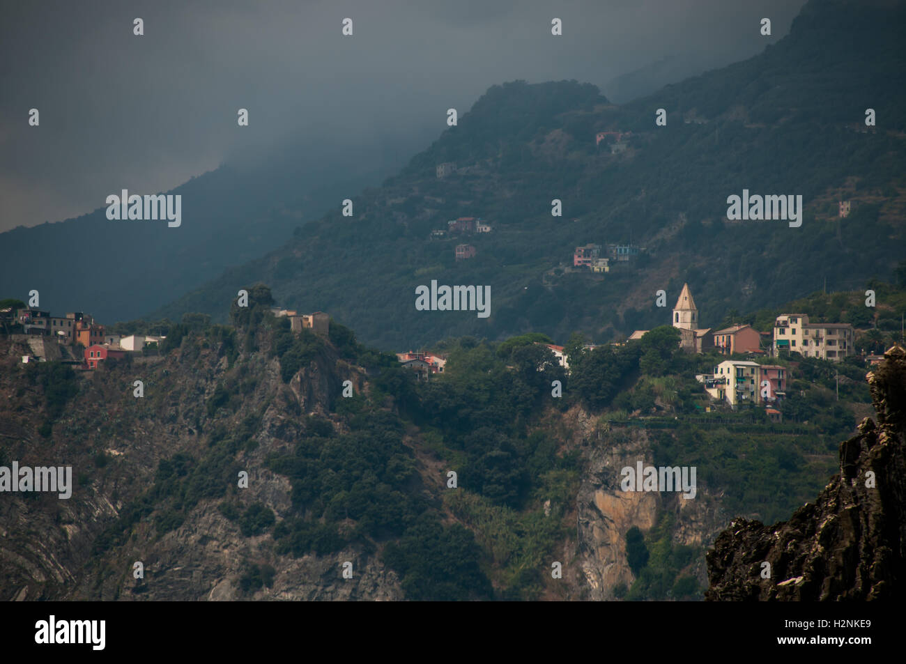 The distant hillside village of Corniglia under stormy skies, photographed from Manarola, Cinque Terre, Italy, September Stock Photo