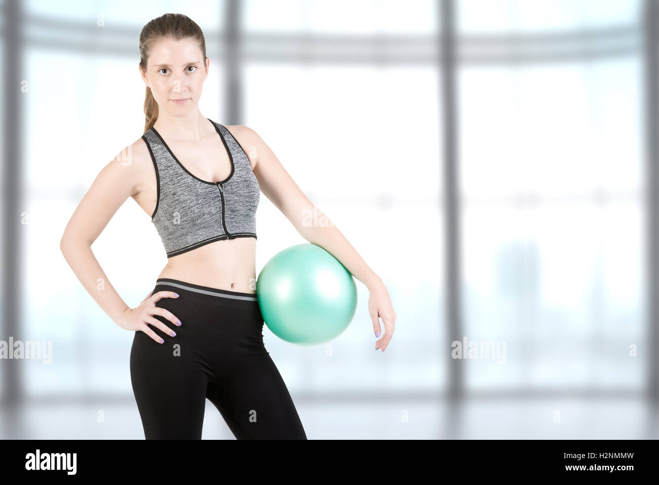 Fit woman standing and holding a pilates ball, in a gym Stock Photo