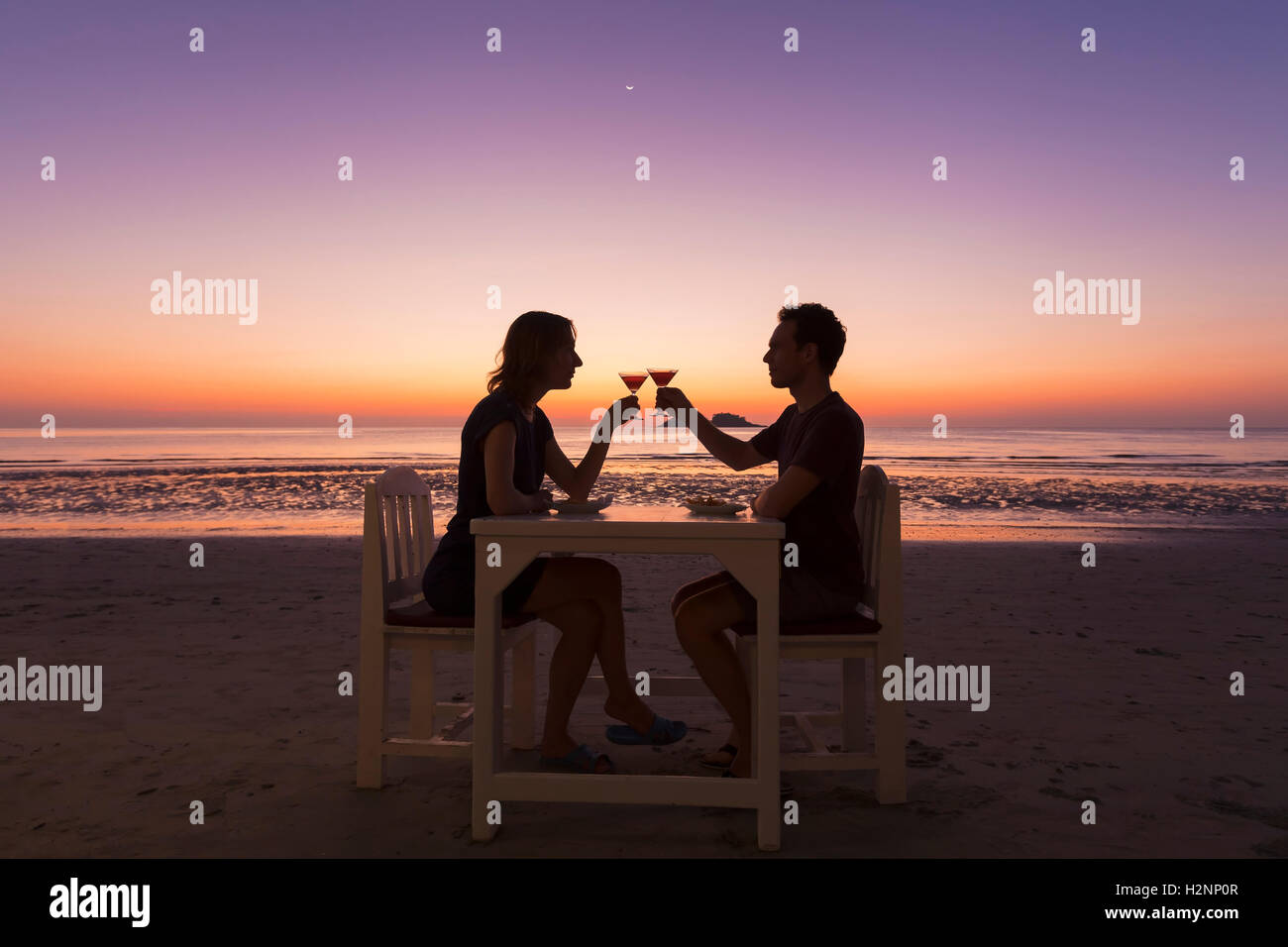 Young couple having a diner at a beach restaurant, tropical resort, sunset Stock Photo