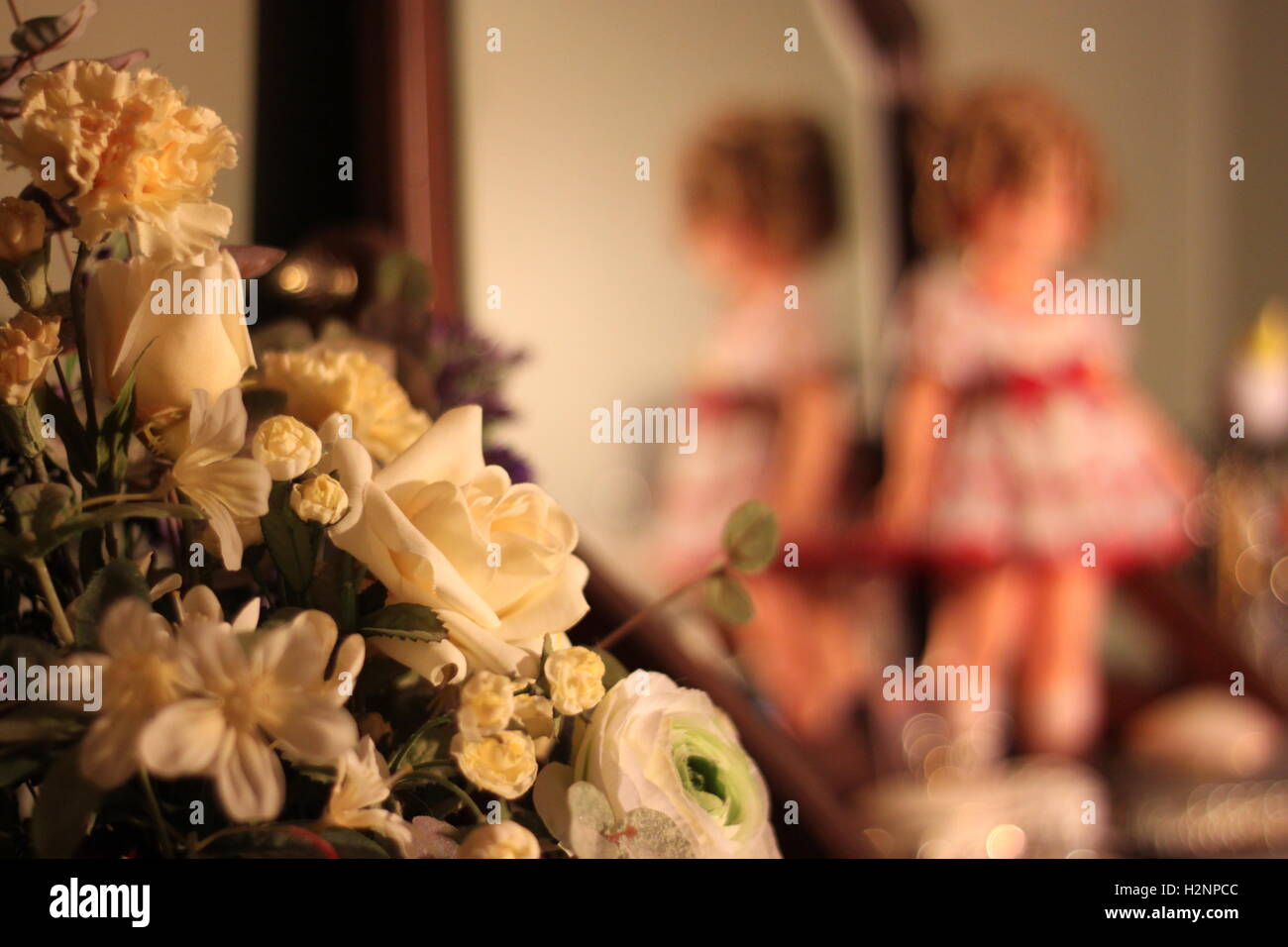 vintage flowers on display in bedroom with vintage doll in background Stock Photo