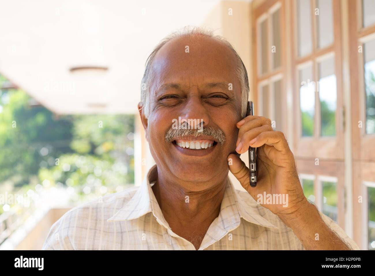 Closeup portrait, happy bald pensioner enjoying phone conversation. Call me on my cell phone, isolated outdoors outside Stock Photo