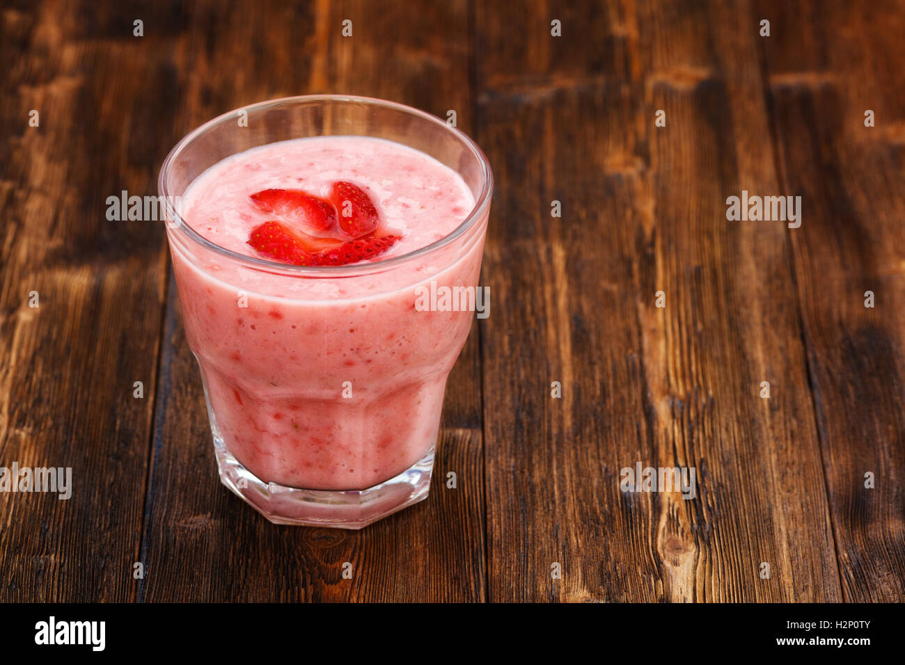 Strawberry milk smoothie in a glass, wooden background Stock Photo