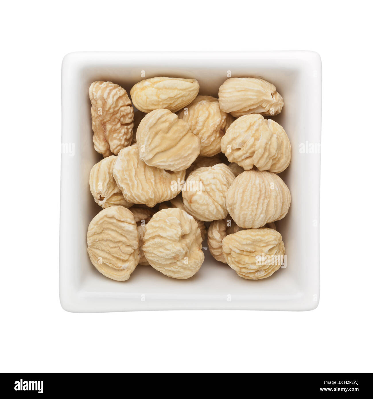 Dried unshelled chestnuts in a square bowl isolated on white background Stock Photo