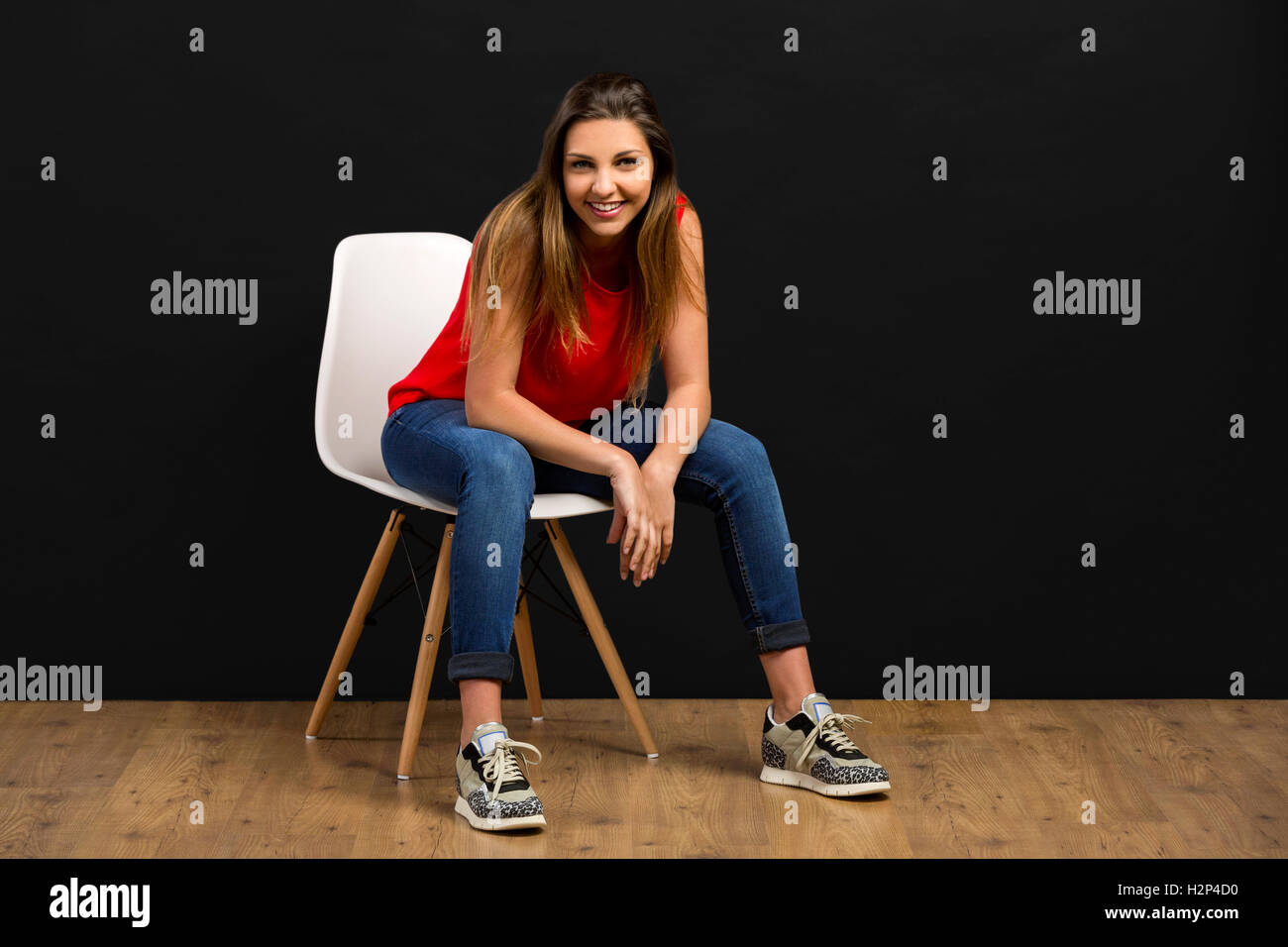 Beautiful young woman sitting on chair and smiling Stock Photo - Alamy
