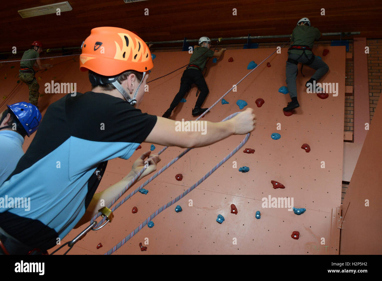 A climber makes process up a climbing wall to achieve his goal of reaching the top. Stock Photo