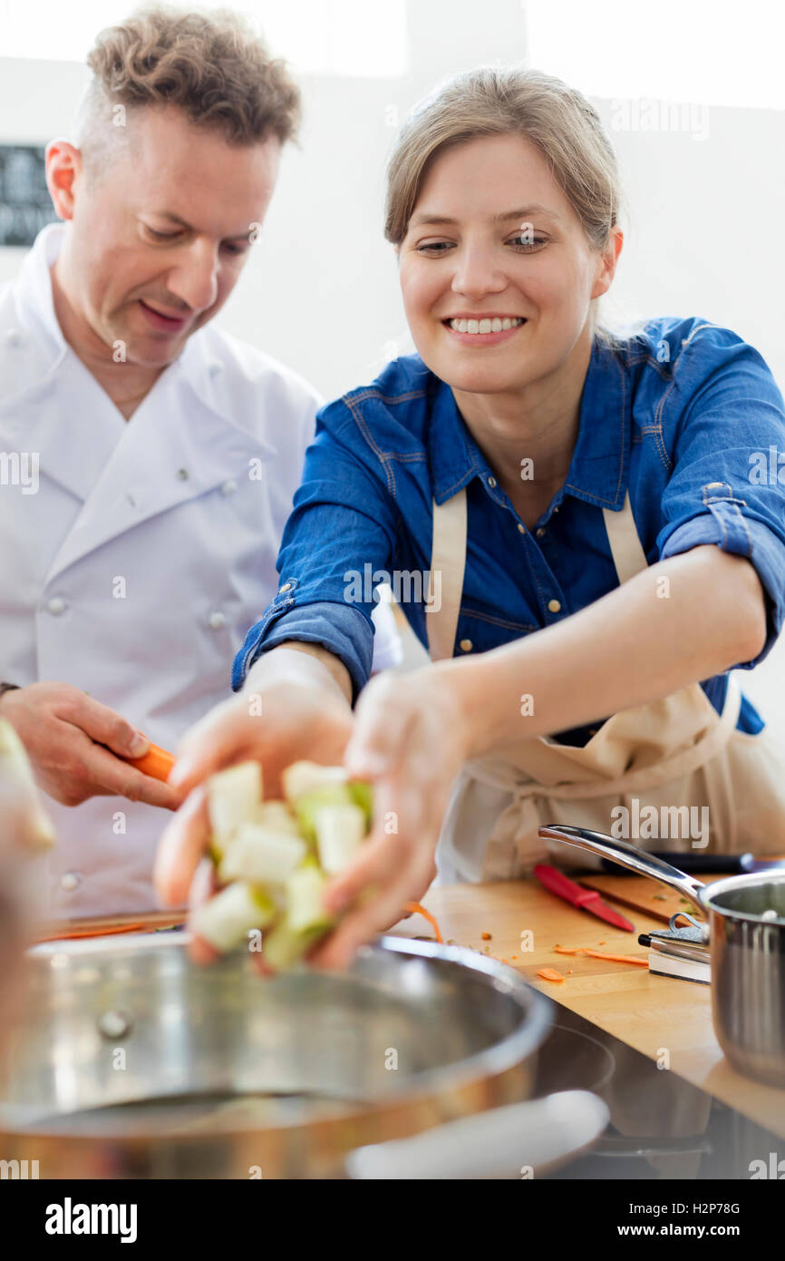 Woman placing food in pot in cooking class kitchen Stock Photo Alamy