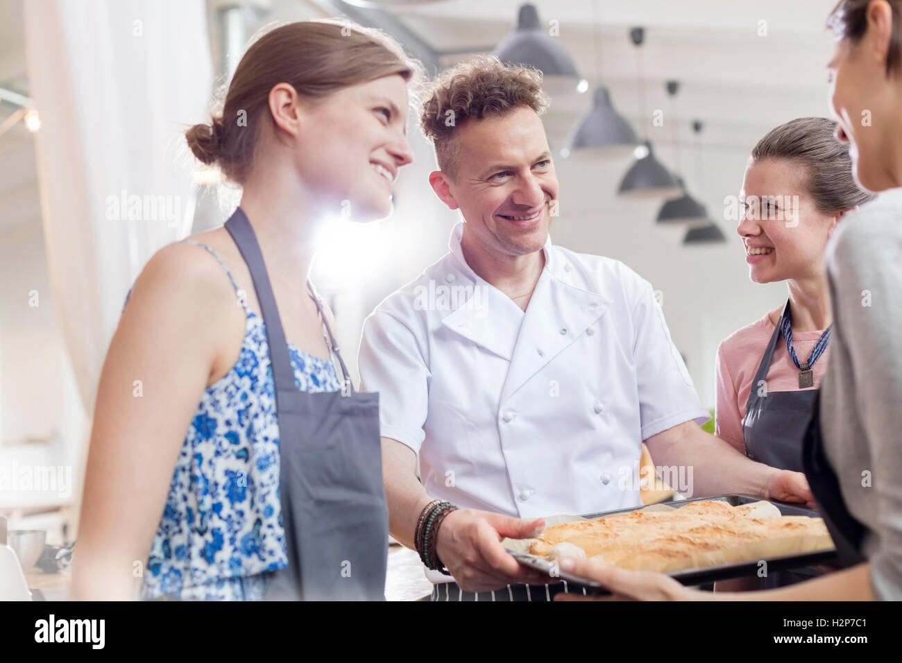 Smiling chef teacher and students in cooking class kitchen Stock Photo