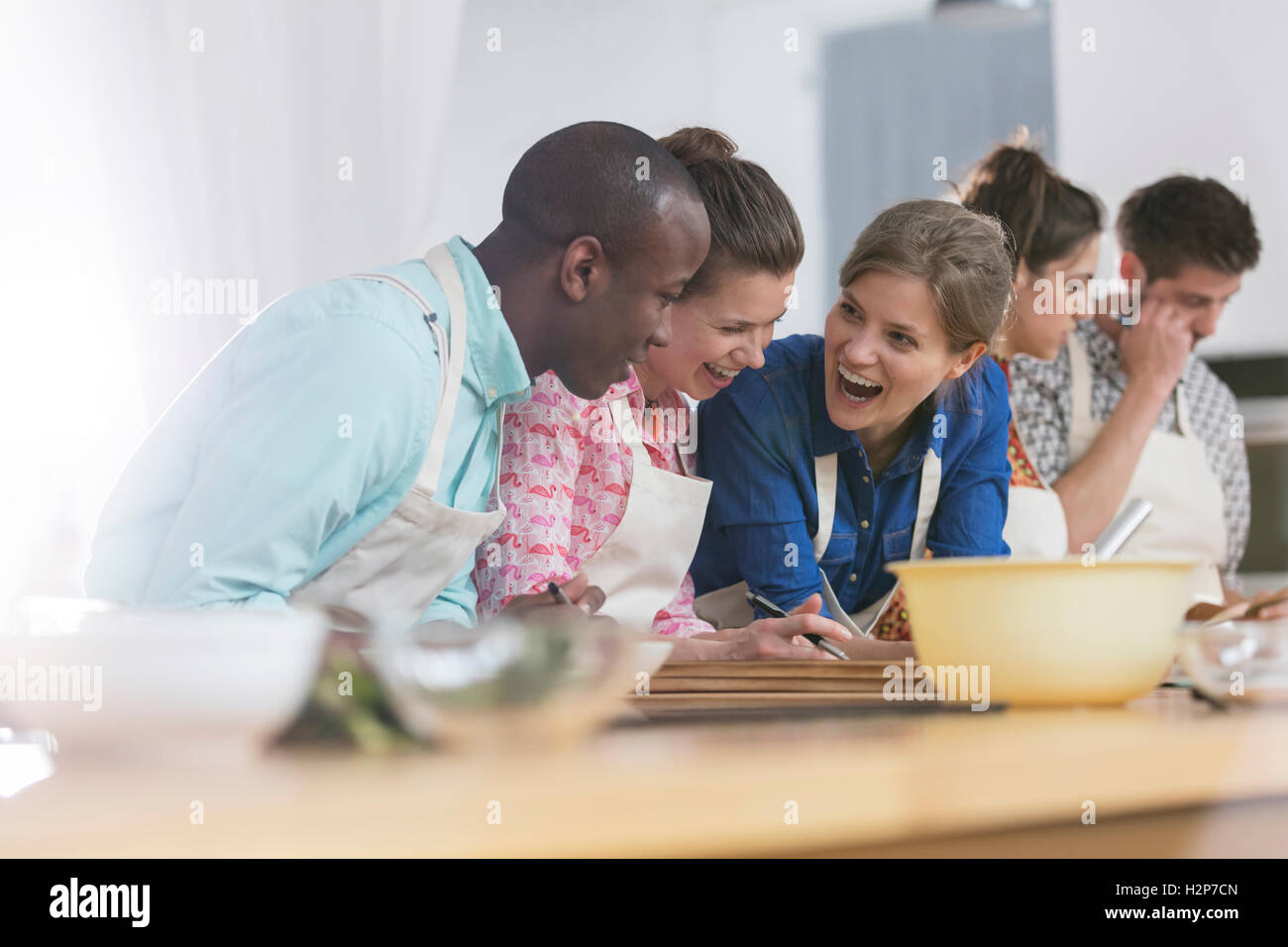 Laughing friends enjoying cooking class in kitchen Stock Photo