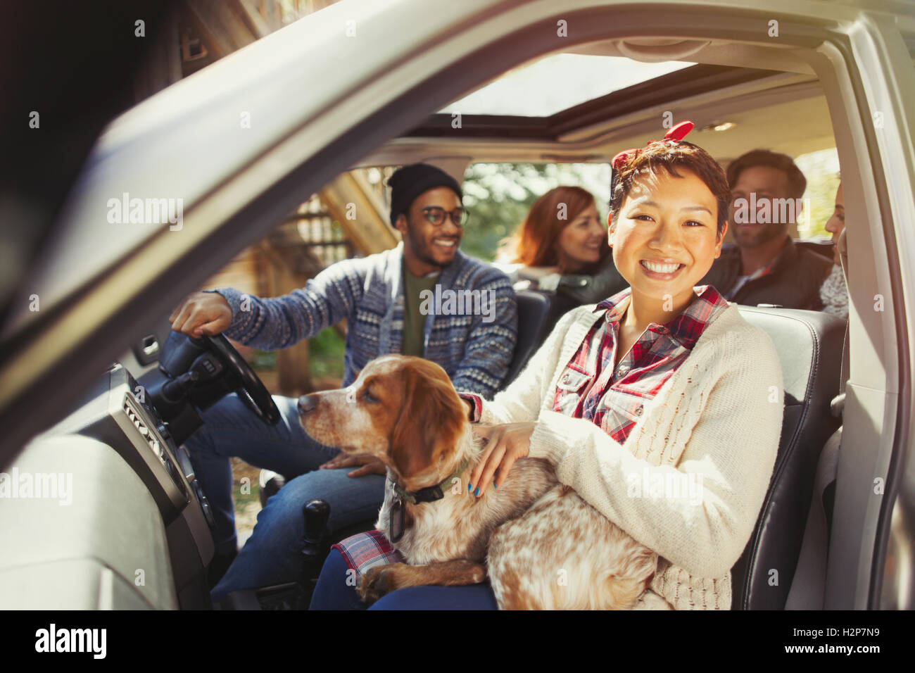 Portrait smiling woman with dog on lap in car with friends Stock Photo