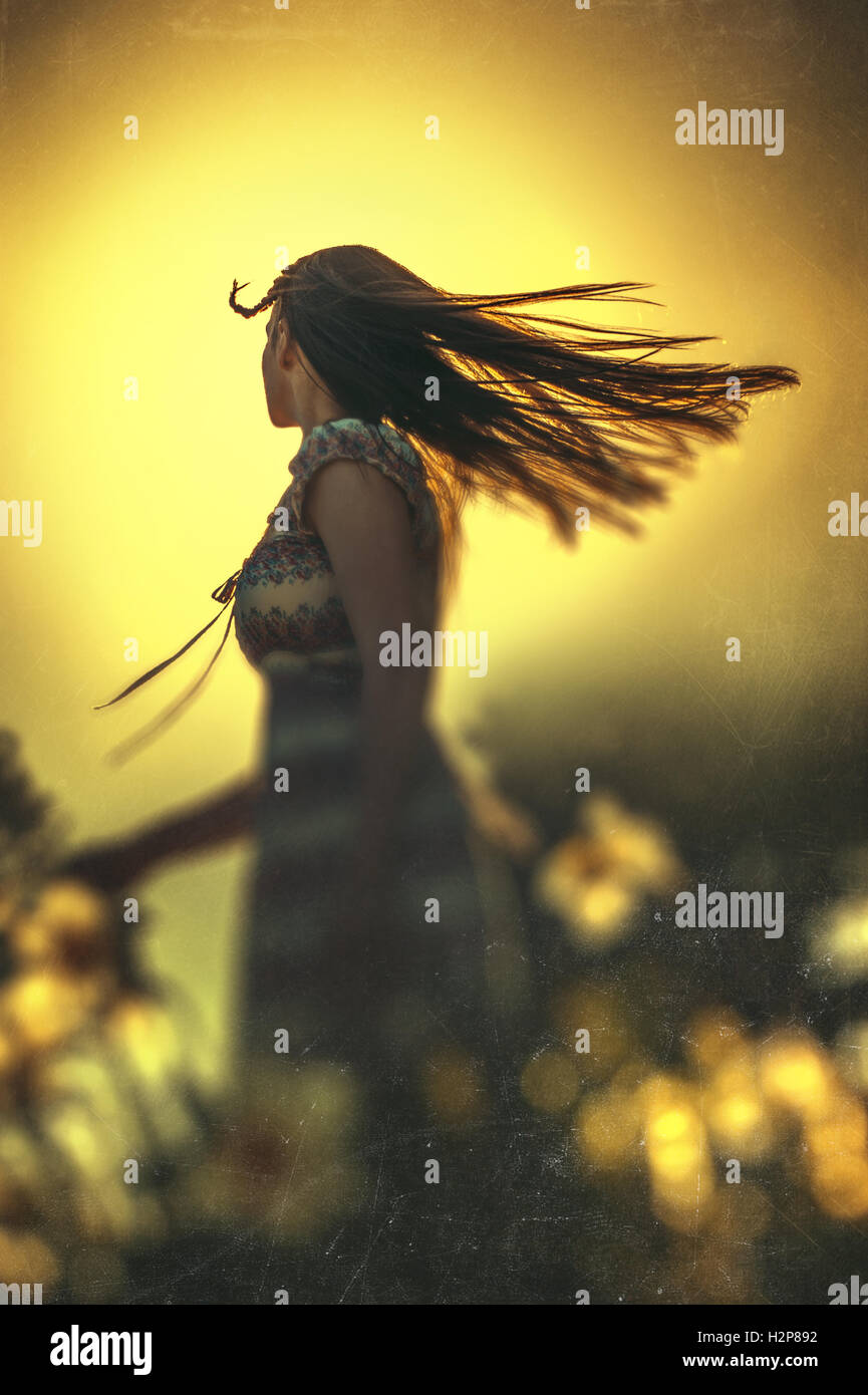 happy young woman dancing in summer meadow with yellow flowers Stock Photo