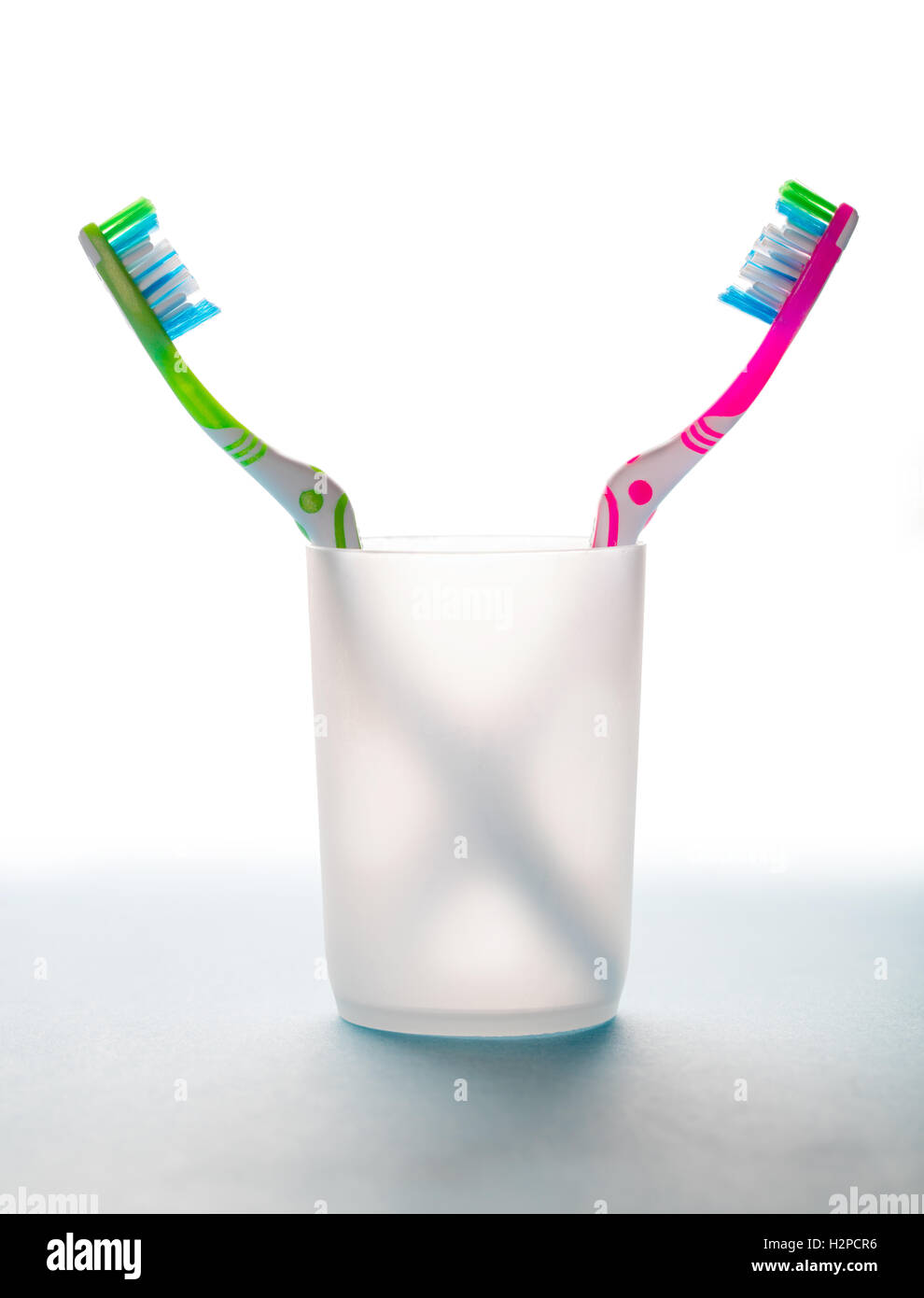 two toothbrushes in a glass on white background Stock Photo - Alamy