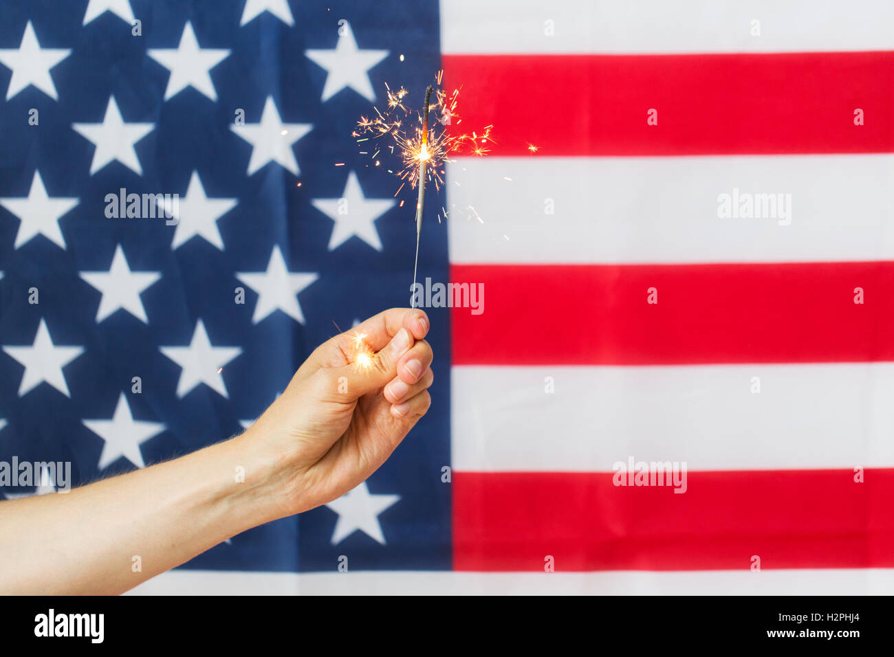 close up of hand with sparkler over american flag Stock Photo - Alamy