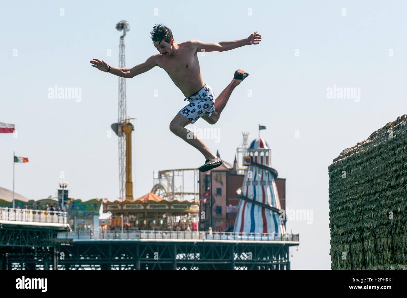 Teenagers jumping from groynes on Brighton beach into the sea on a hot afternoon. Stock Photo