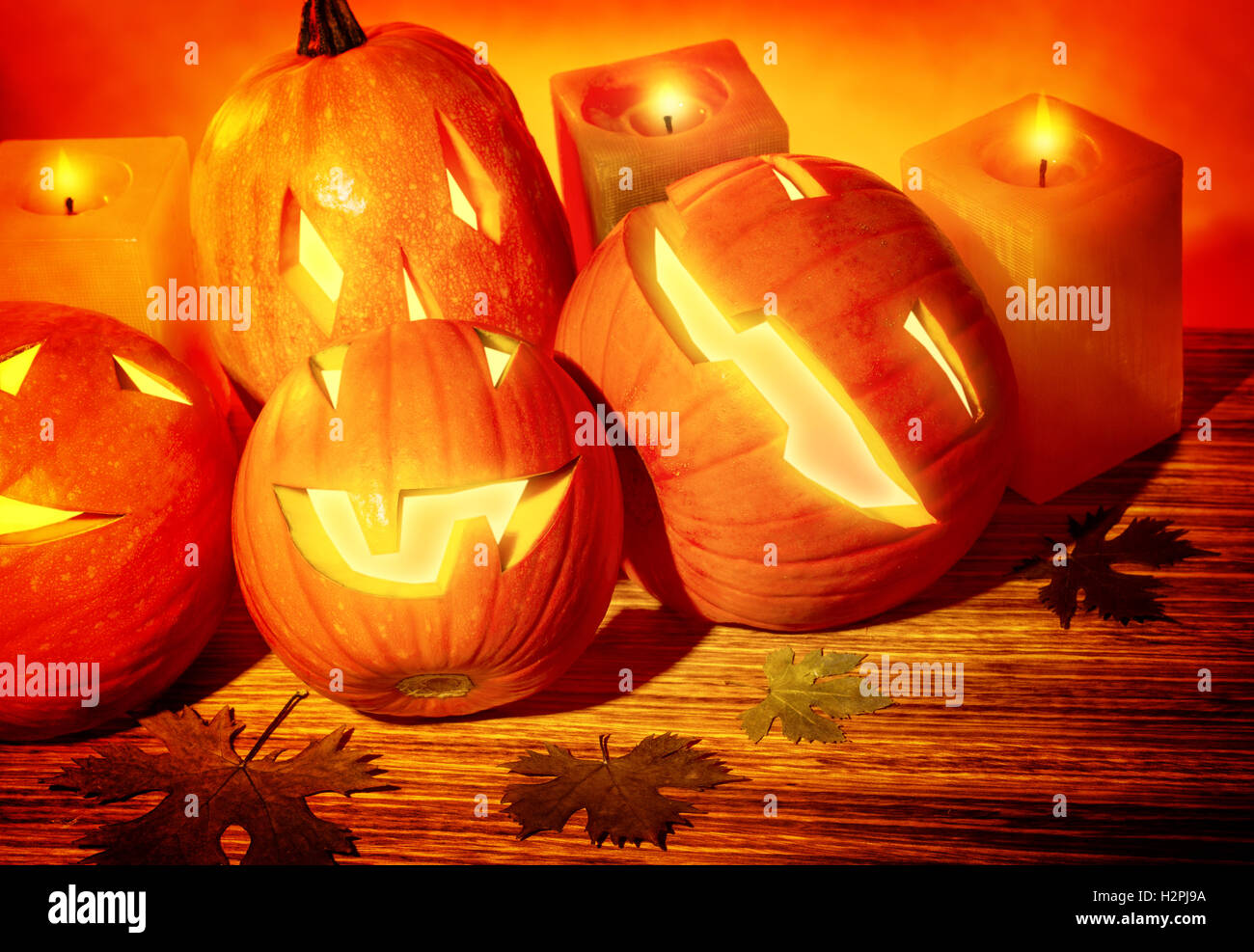 Closeup photo of a carved pumpkins with scary faces and glowing candles on the table, festive party decoration for Halloween Stock Photo