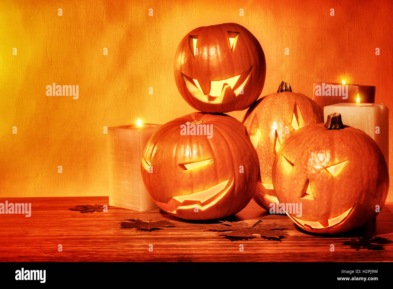 Grunge style photo of a carved pumpkins with scary faces and glowing candles on the table, festive party decoration Stock Photo