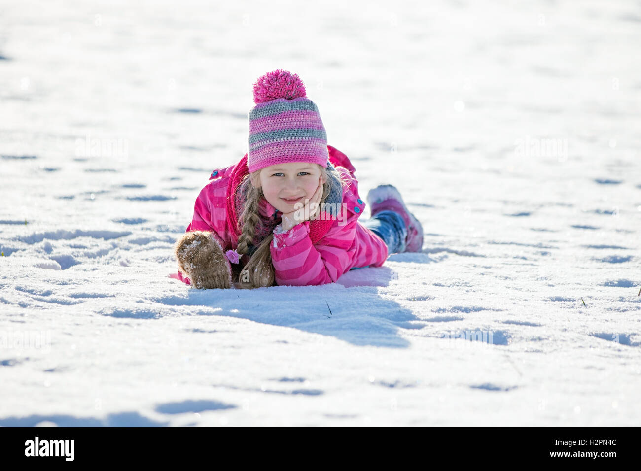 Winter image of a Girl laying down on the snow feeling happy Stock Photo