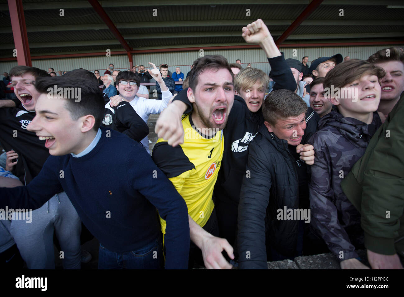 Visiting fans in the away end celebrating with midfielder Ian McFarland after East Stirlingshire took on Edinburgh City in the second leg of the Scottish League pyramid play-off at Ochilview Park, Stenhousemuir. The play-offs were introduced in 2015 with the winners of the Highland and Lowland Leagues playing-off for the chance to play the club which finished bottom of Scottish League 2. Edinburgh City won the match 1-0 giving them a 2-1 aggregate victory making them the first club in Scottish League history to be promoted into the league. Stock Photo
