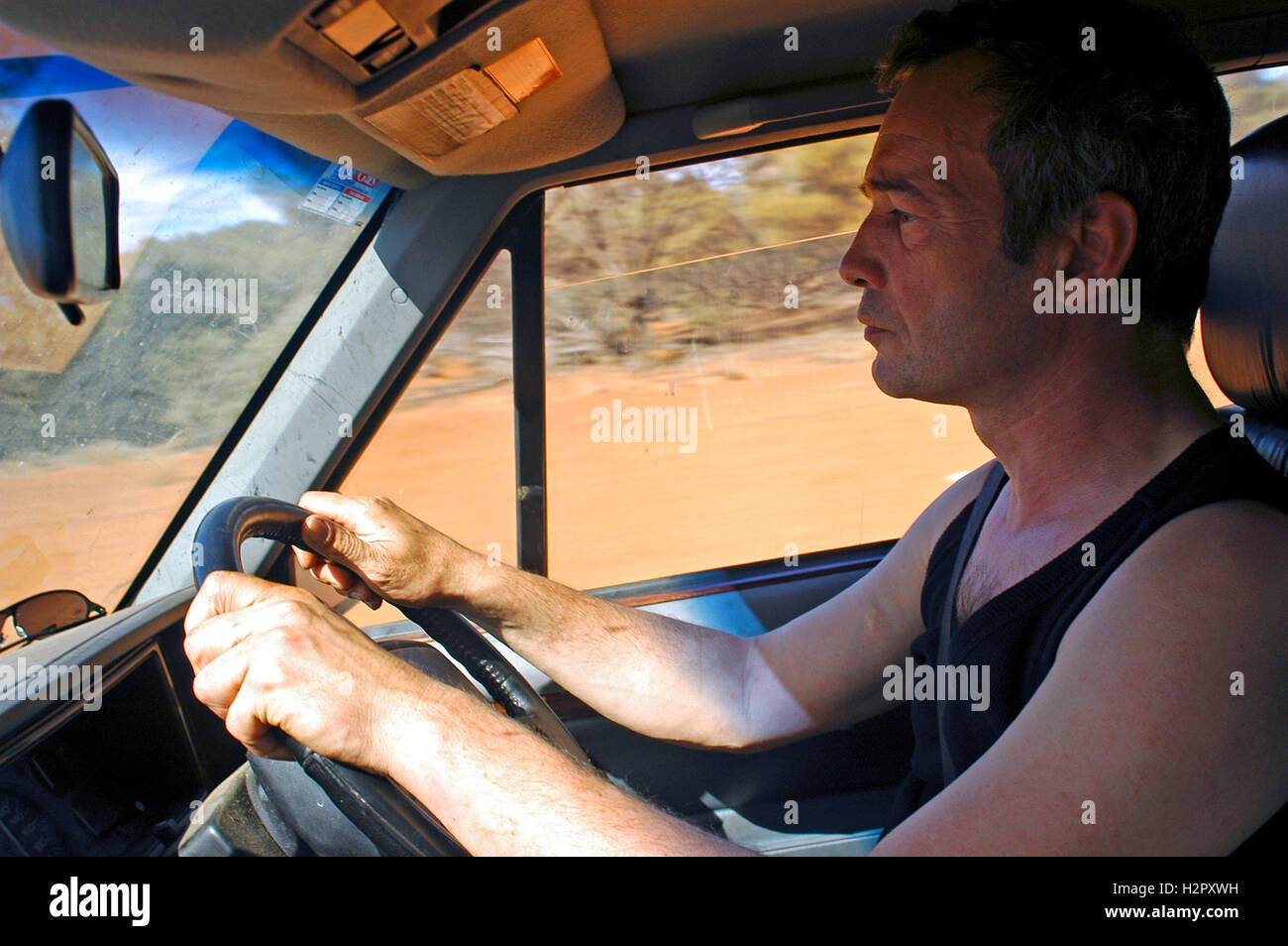 Australian driver driving on a road with the sun in his eyes Stock