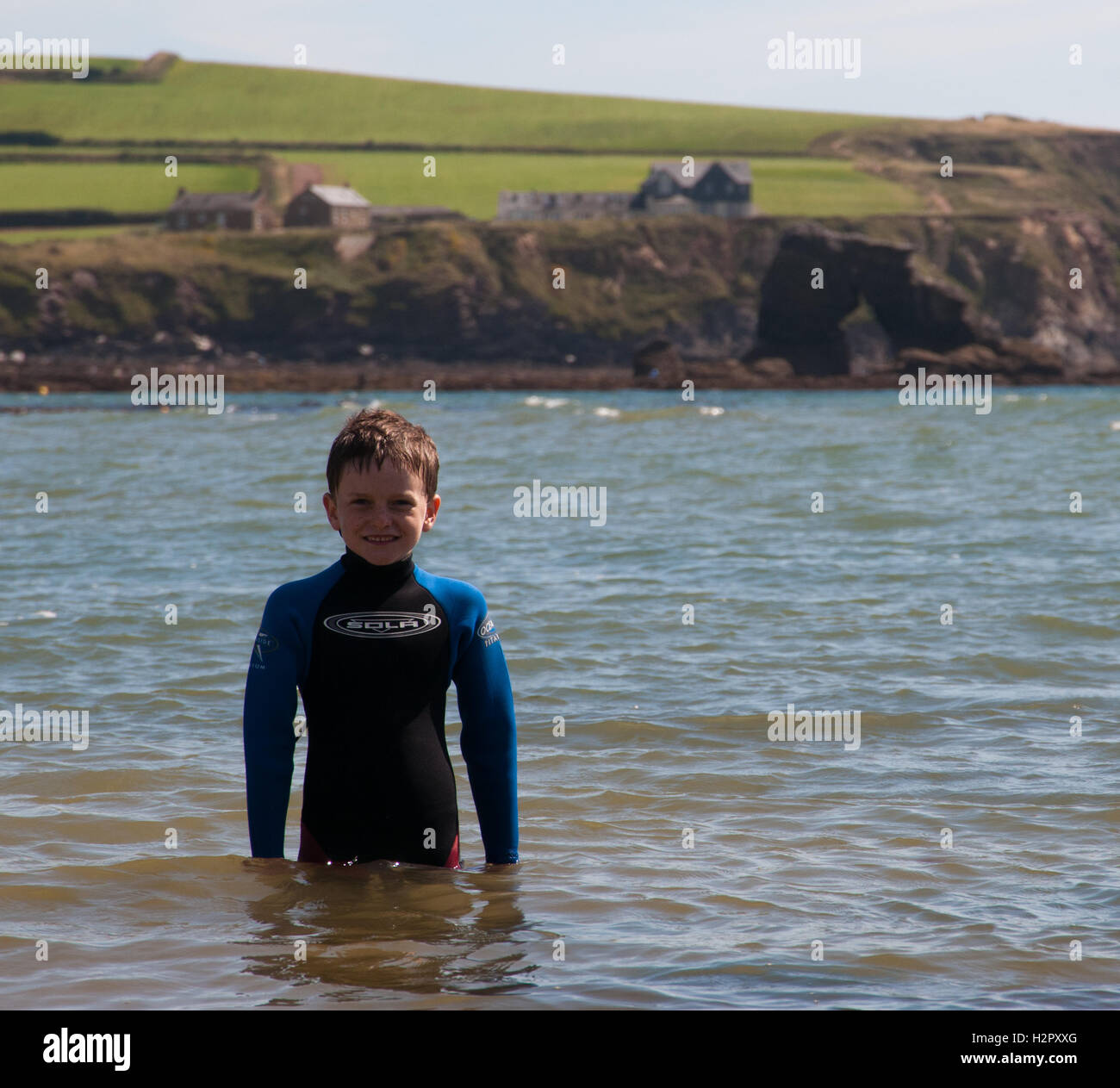 Boy standing in the sea with Thurlestone Rock in the background Stock Photo