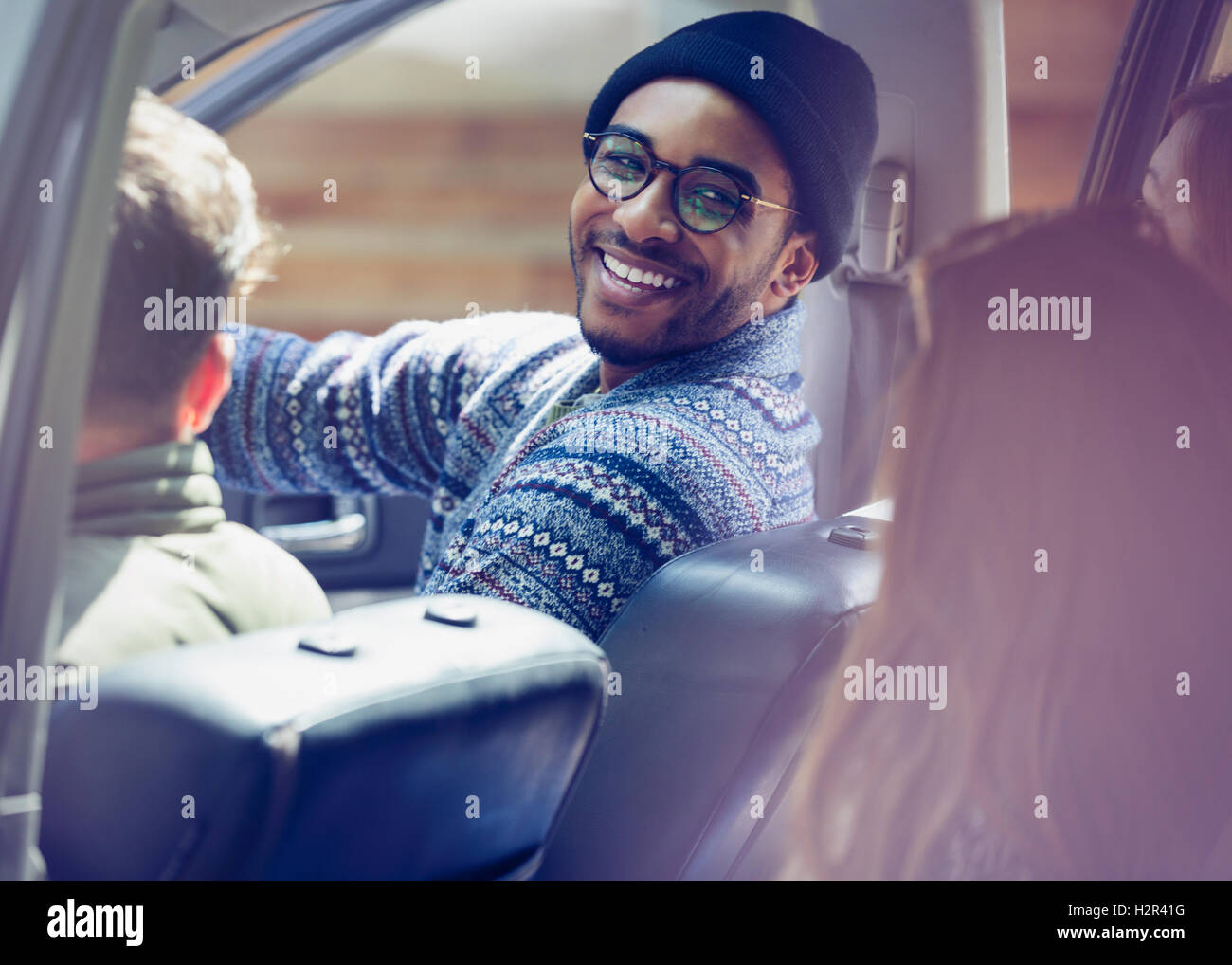 Smiling man riding in car with friends Stock Photo
