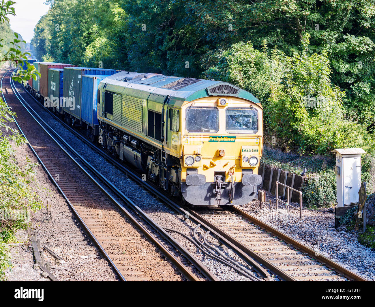A Freightliner container train hauled by a Class 66 diesel locomotive in Freightliner livery passes St Cross near Winchester. Stock Photo