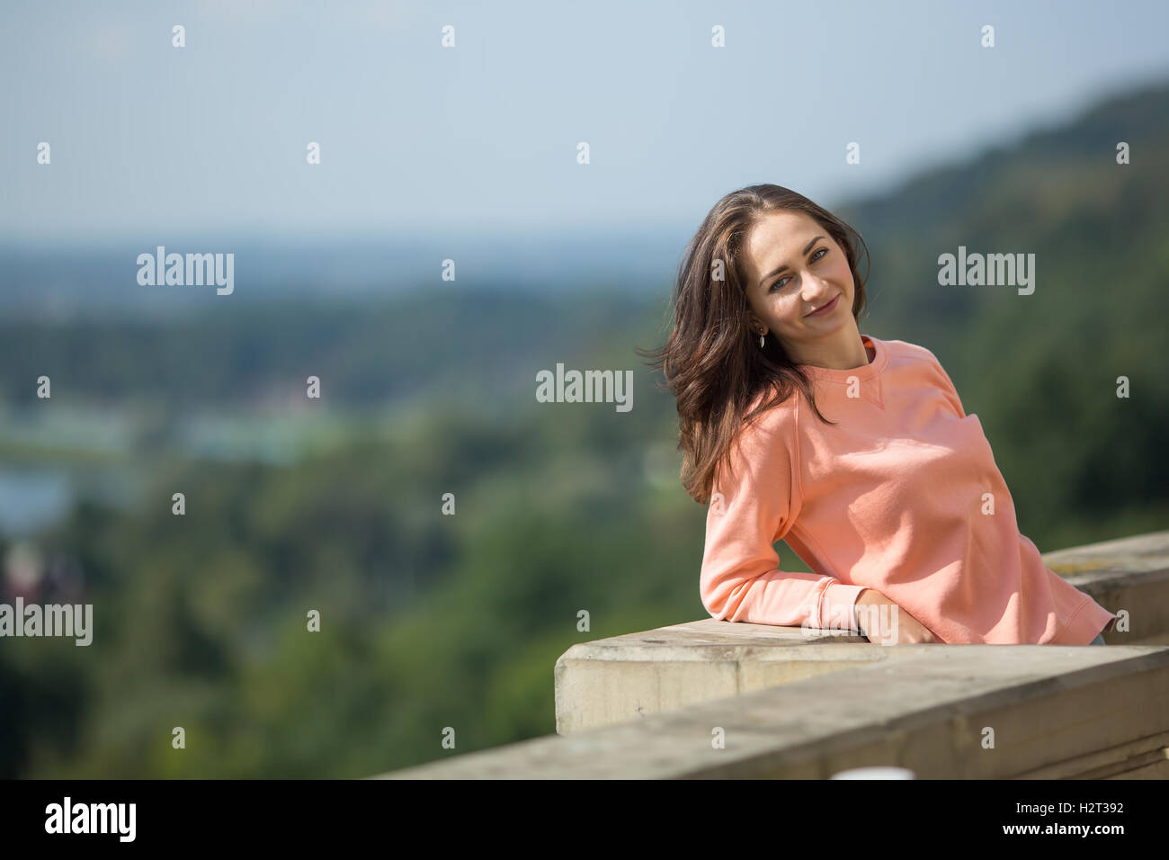 Cute young lady standing at the parapet. Stock Photo