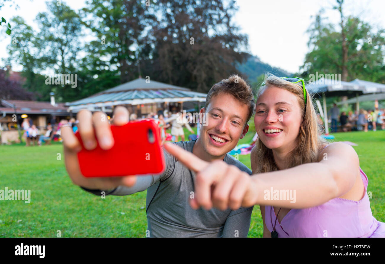 Young man and young woman smiling, looking at mobile phone, Bavaria, Germany Stock Photo