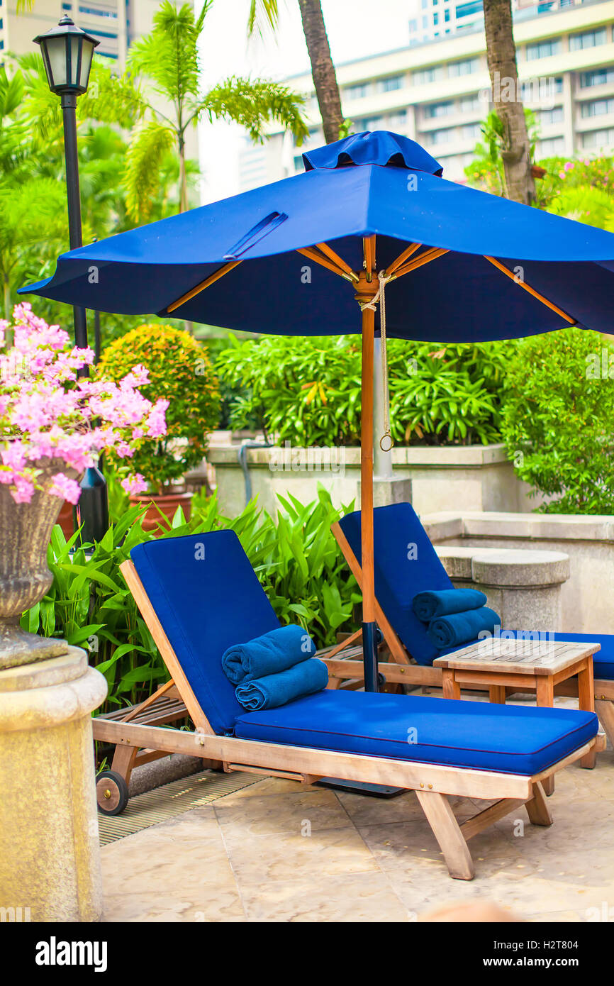 Two blue loungers with umbrellas near swimming pool in luxury hotel
