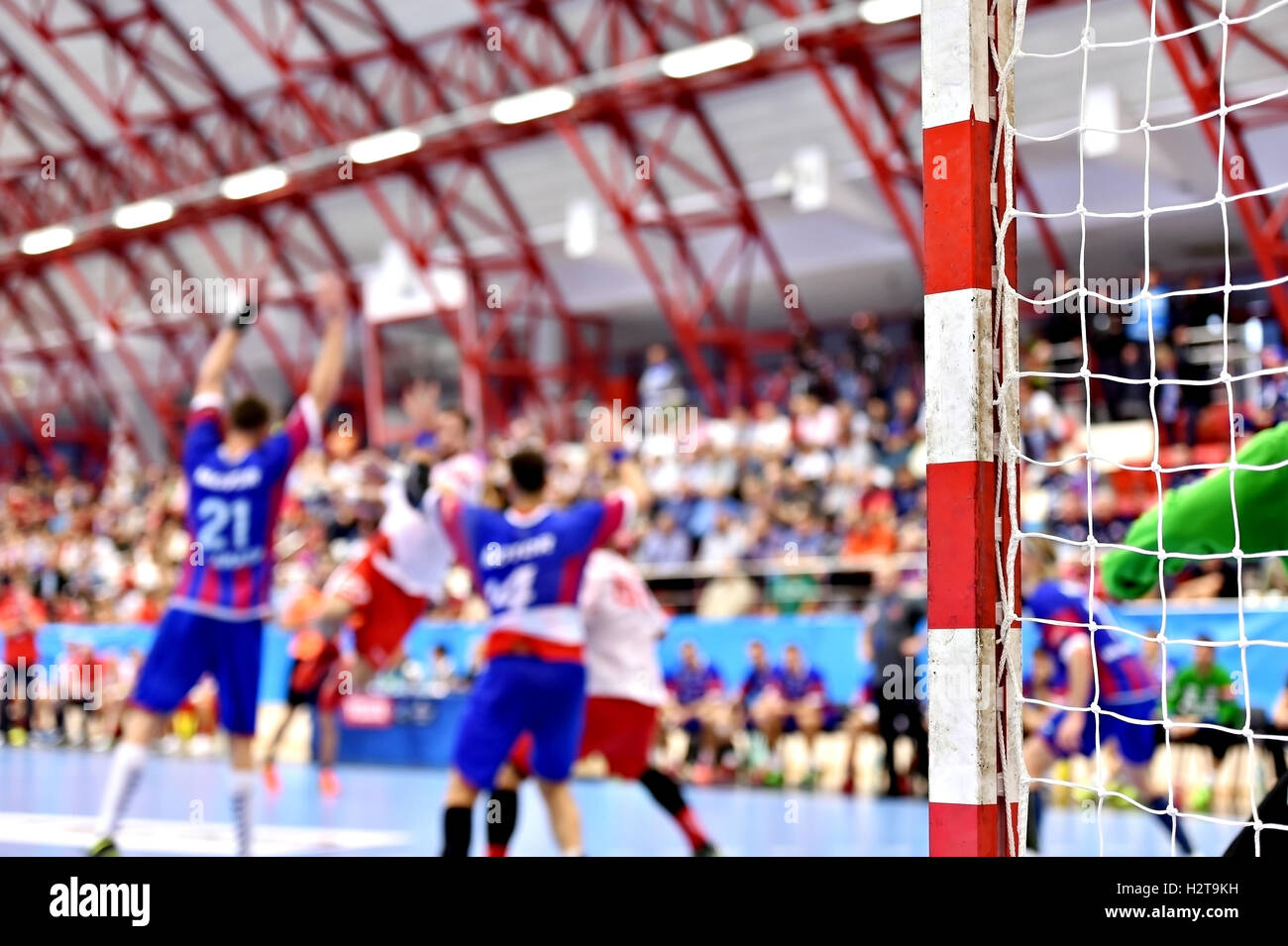 Handball match scene with goalpost and players in the background Stock Photo