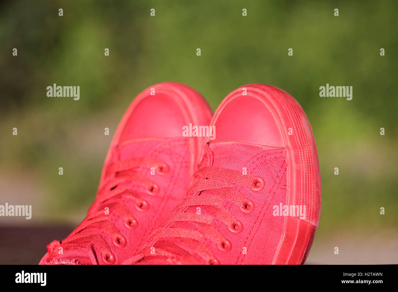 Red sneakers on green blured defocused background Stock Photo