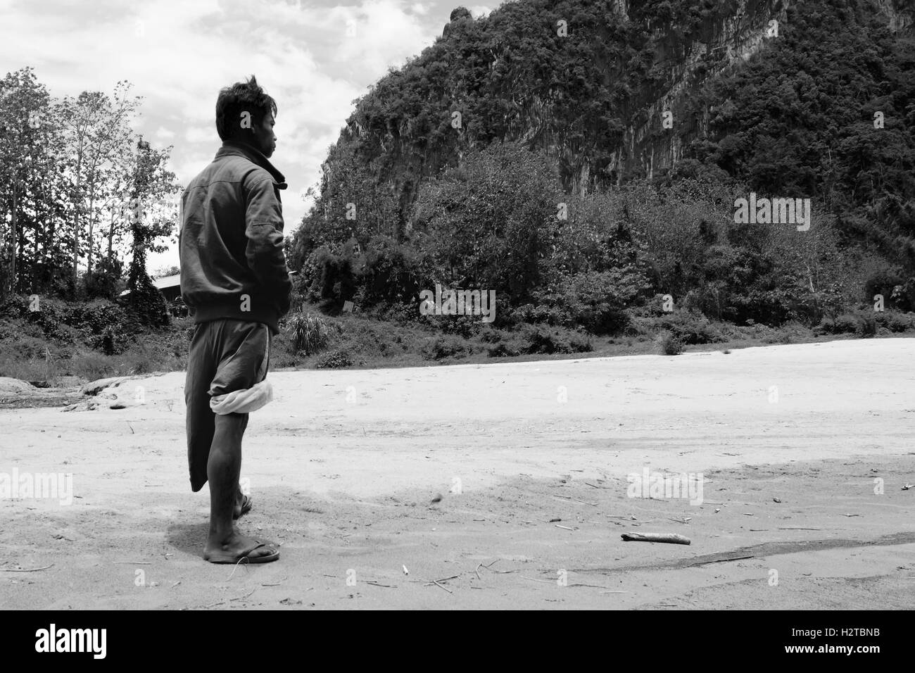 Laotian man facing the mountain on the Nam river bank - Laos Stock Photo
