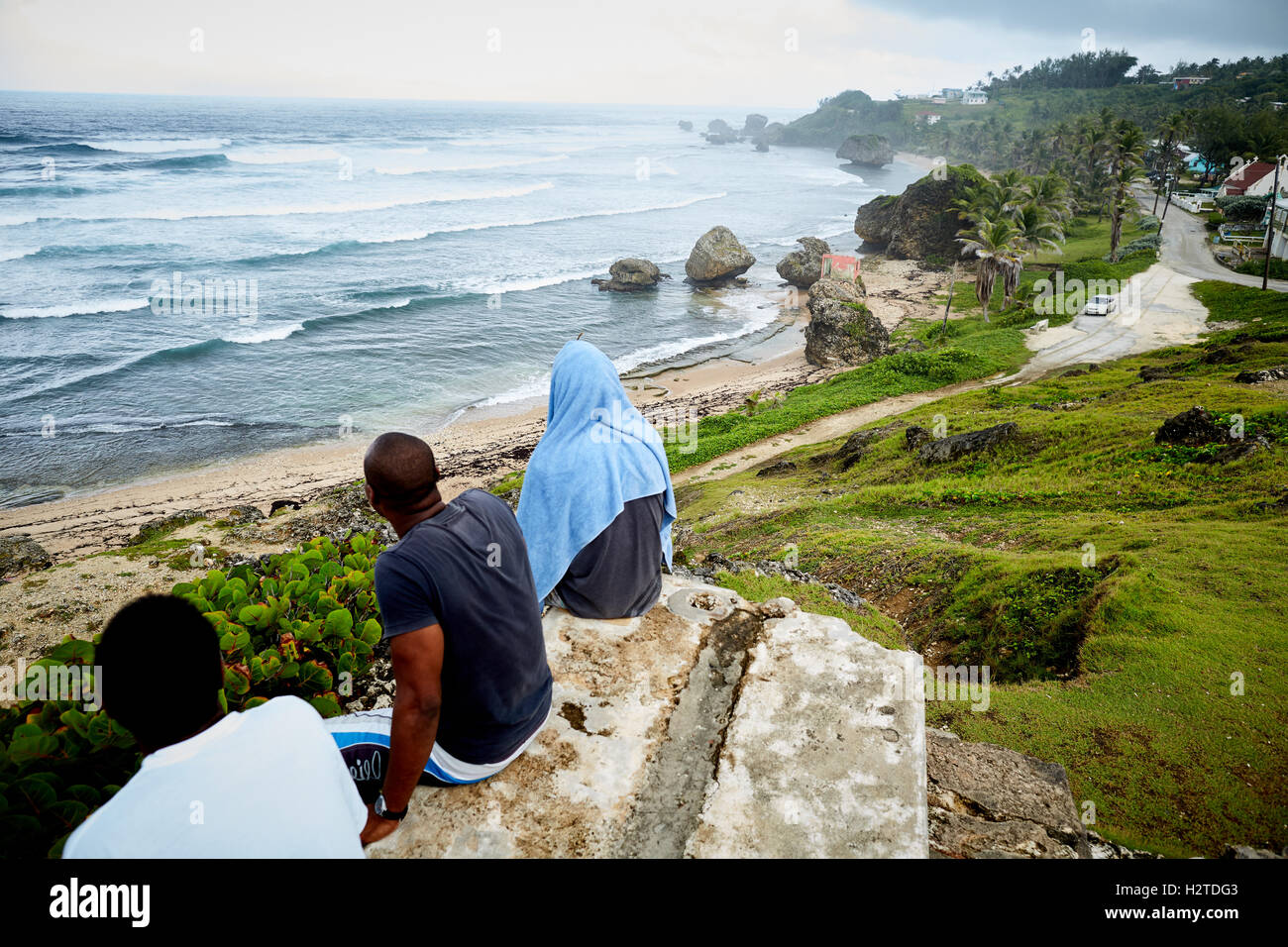 Barbados Bathsheba atlantic coast view ocean  local men boys sat looking out to sea relaxed resting sat on stone beech Elevated Stock Photo