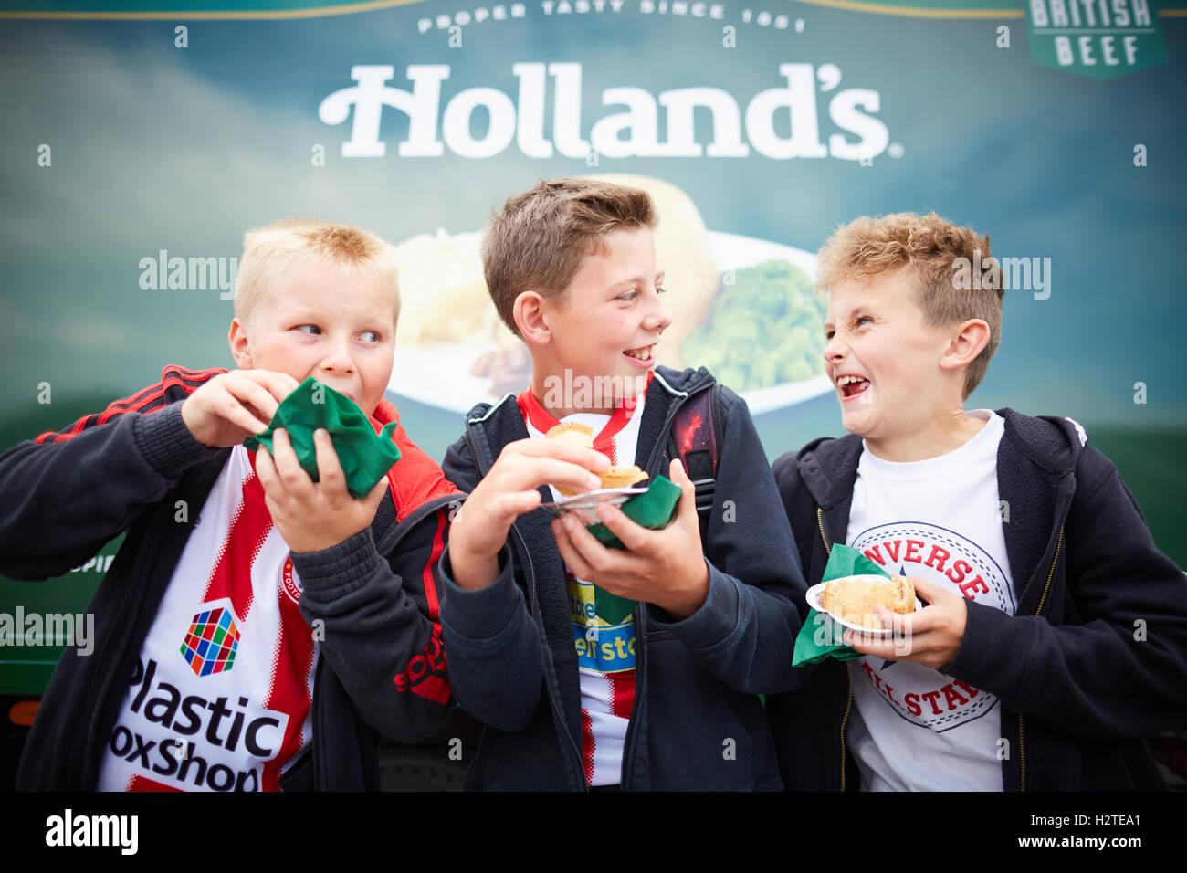 Football fans eating pies Hollands   Accrington Stanly FC fans match game eating pies happy laughing Young kids children youngst Stock Photo